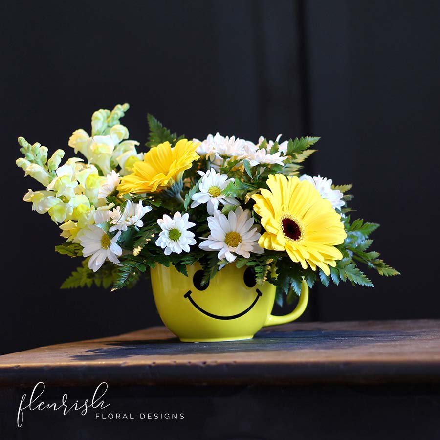 Don't Worry Be Happy Don't Worry Be Happy - A cheery arrangement in a large happy face mug filled with yellow snapdragons, daisies and yellow gerbera daisies- upgrade for roses as well.