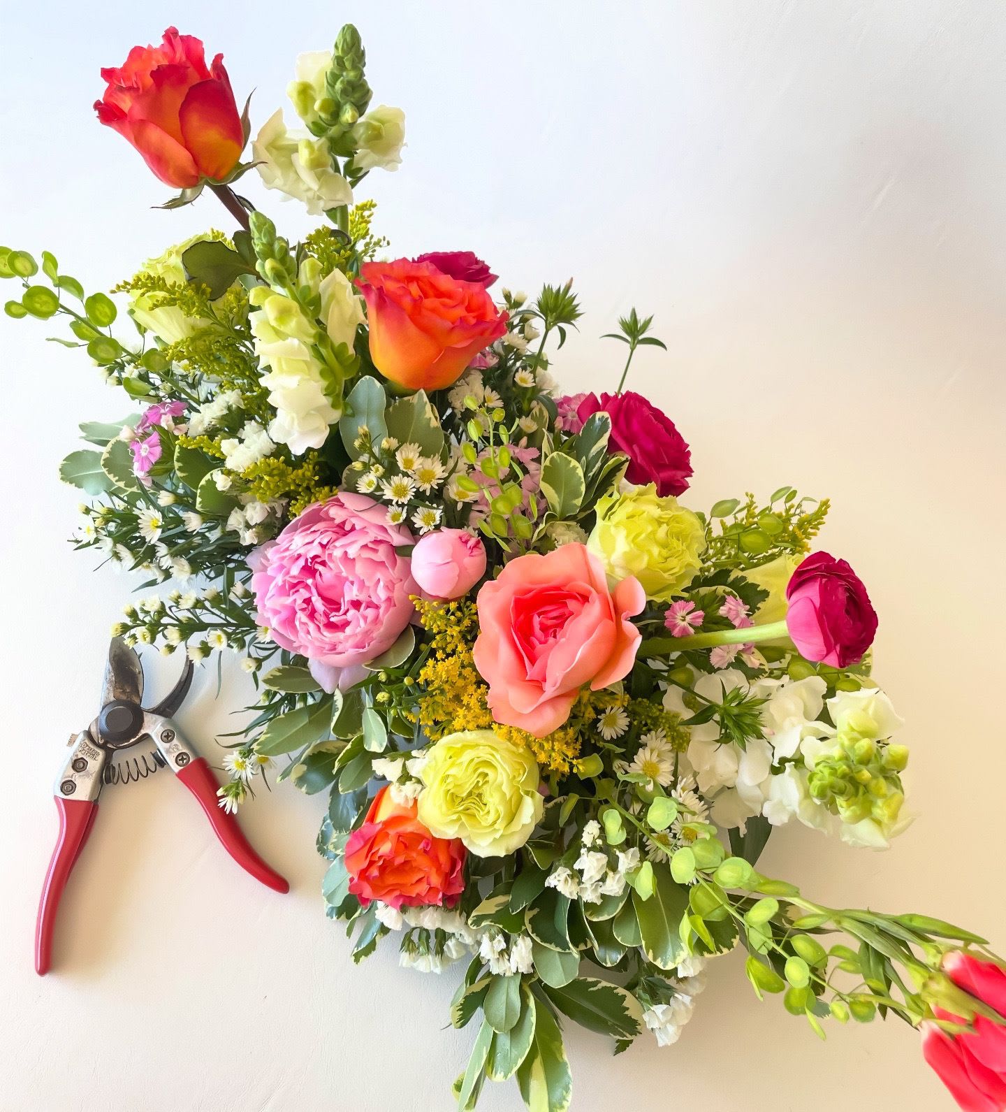 Designer's Choice-Long and Low Centerpiece - The perfect addition to your (or a friend's) tablescape! A long, low double-sided arrangement full of seasonal tones.  Pictured is the standard price.  Deluxe and premium pricing will have more blooms and be larger! Each centerpiece is a designer's choice, thoughtfully curated based on weekly availability and seasonal vibes. We source flowers from a variety of trusted suppliers, receiving fresh shipments multiple times a week, ensuring that every arrangement is one-of-a-kind and full of seasonal blooms. 