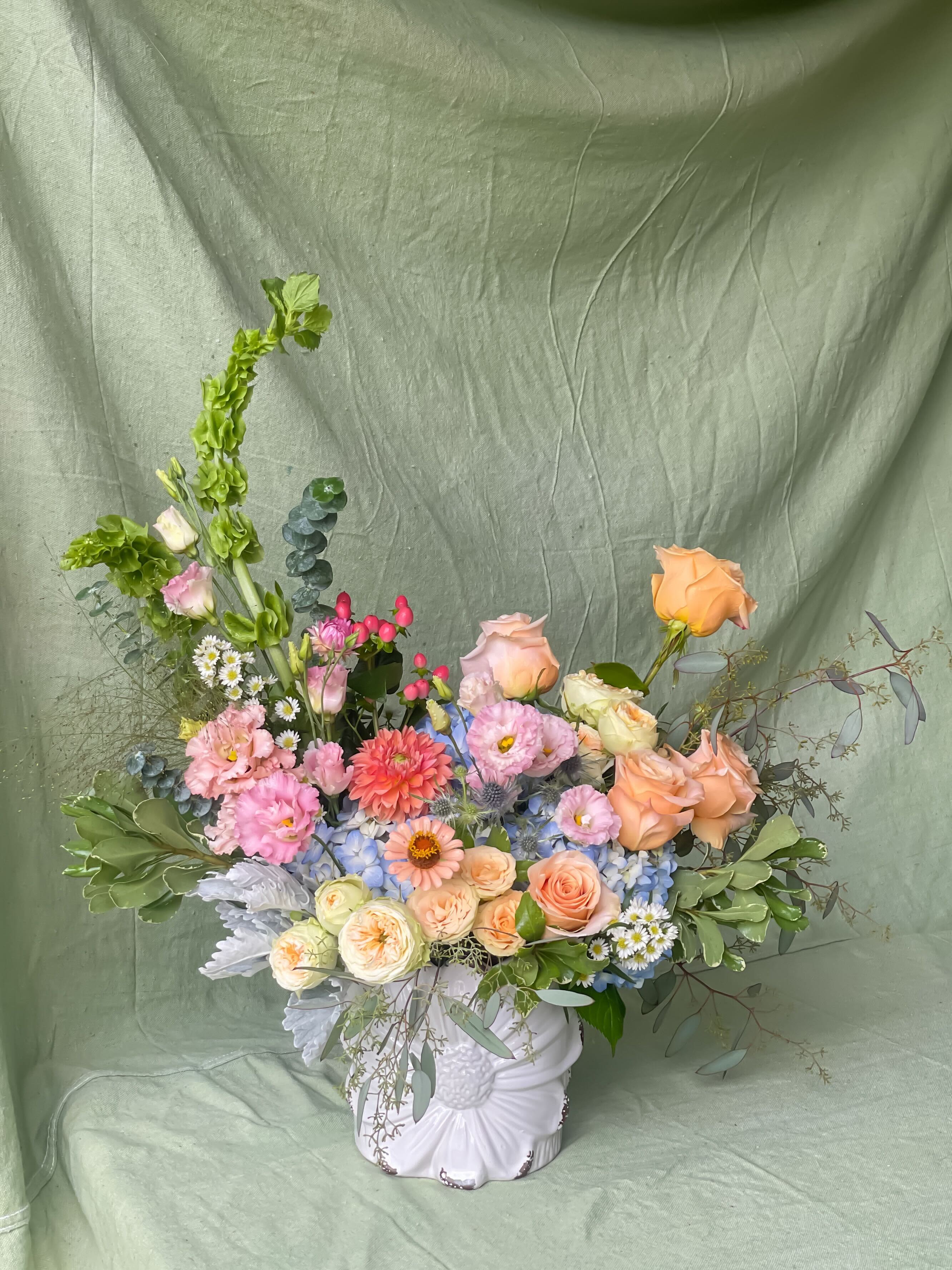 Grand-Florist's Choice - Make a bold impression with our statement piece, a stunning arrangement packed with premium and novelty blooms, artfully arranged in a garden-style design. This whimsical creation combines lush textures and vibrant colors, offering a captivating display that is sure to be the centerpiece of any room. Each arrangement is thoughtfully crafted based on weekly and seasonal availability, ensuring a fresh, one-of-a-kind masterpiece with every order. Perfect for those looking to add a touch of luxury and natural beauty to their space, this arrangement will bring warmth and elegance to any occasion.