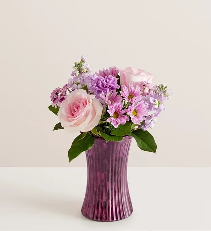 Mother’s Day Daydream Bouquet  - All-around arrangement with pink roses; lavender carnations, daisy poms, button poms and stock; purple monte casino; accented with assorted greenery Artistically designed in our exclusive fluted gathering vase in a lovely shade of violet; vintage pressed glass with ribbed detail creates a charming enhancement for the floral arrangement; measures 7.9&quot;H x 5&quot;D Extra large arrangement measures approximately 17&quot;H x 14&quot;W Large arrangement measures approximately 15&quot;H x 13&quot;W Medium arrangement measures approximately 14&quot;H x 12&quot;W Small arrangement does not include monte casino; measures approximately 13&quot;H x 10&quot;W Our florists hand-design each arrangement, so colors and varieties may vary due to local availability