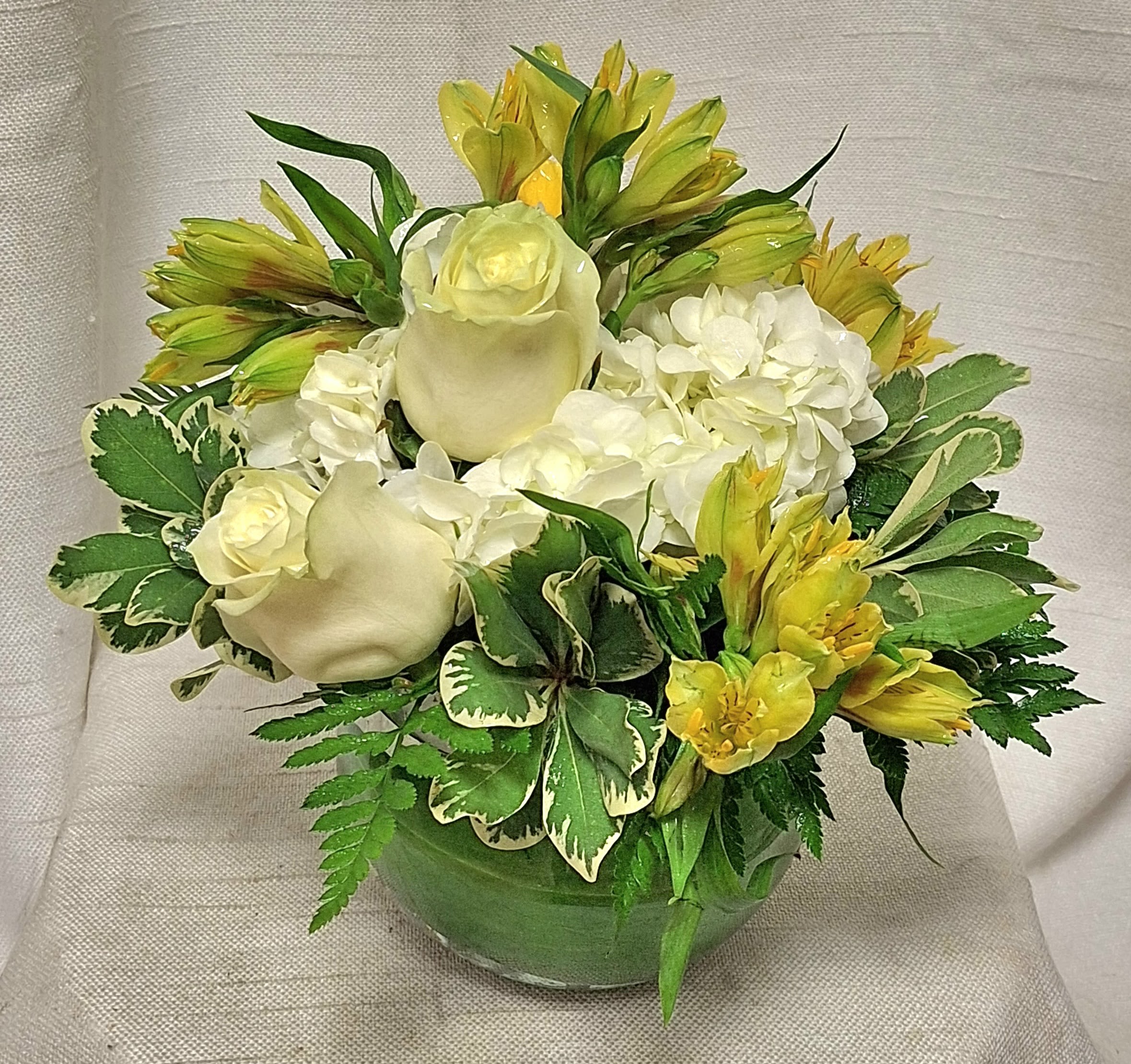 Morning Glow - Introducing the Sweetest Sunrise Arrangement, a captivating floral masterpiece that will surely brighten your day! Expertly crafted by our talented artisans, this arrangement features a striking combination of white and yellow roses, white hydrangea, and yellow alstroemeria, complemented by lush greenery.  