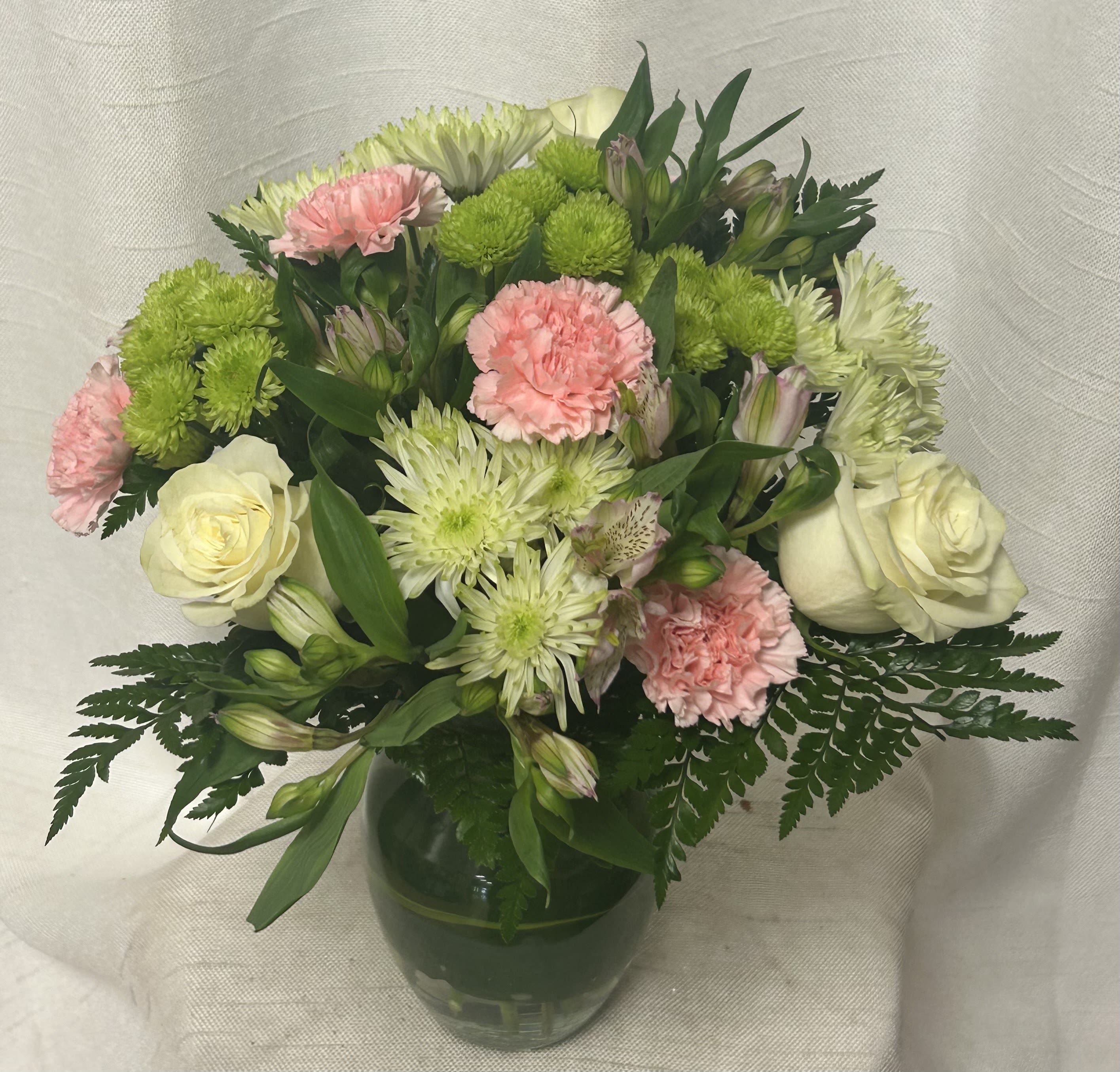 Love's Embrace - Express your love and affection with our enchanting floral arrangement, carefully crafted to symbolize the depth of your emotions for your significant other. This exquisite ensemble features a delightful mixture of blooms, including romantic roses, elegant carnations and mini carnations, vibrant alstroemerias, and fresh greenery to add a touch of natural beauty. 