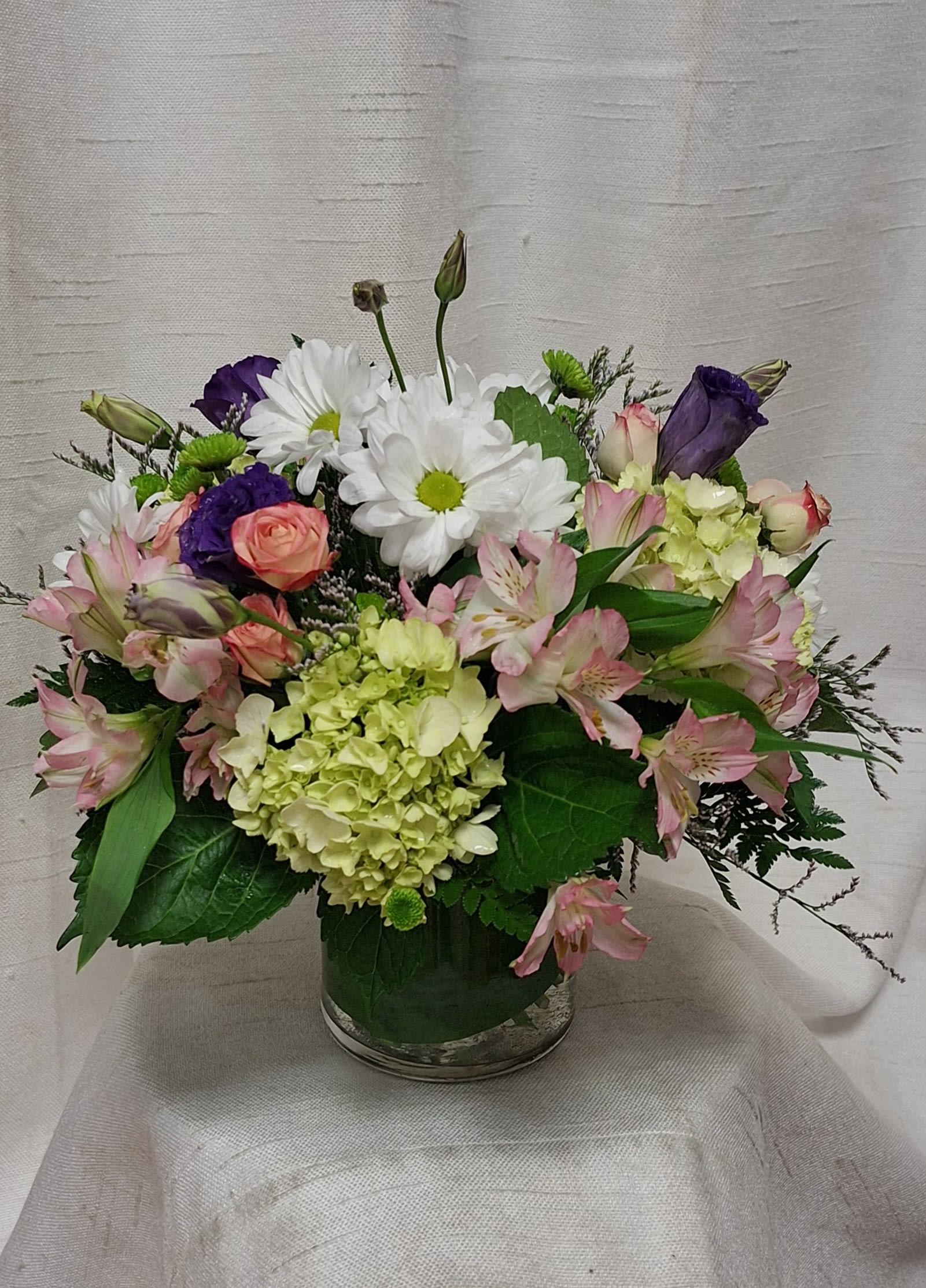 Fluttering Light (BB) - Our charming Fluttering Light flower arrangement, filled with green hydrangea, white daisies, pink carnations, and pink alstroemeria, will leave you enchanted with its simple beauty. This delightful arrangement captures the essence of springtime, radiating a sense of cheerfulness, joy, and optimism.