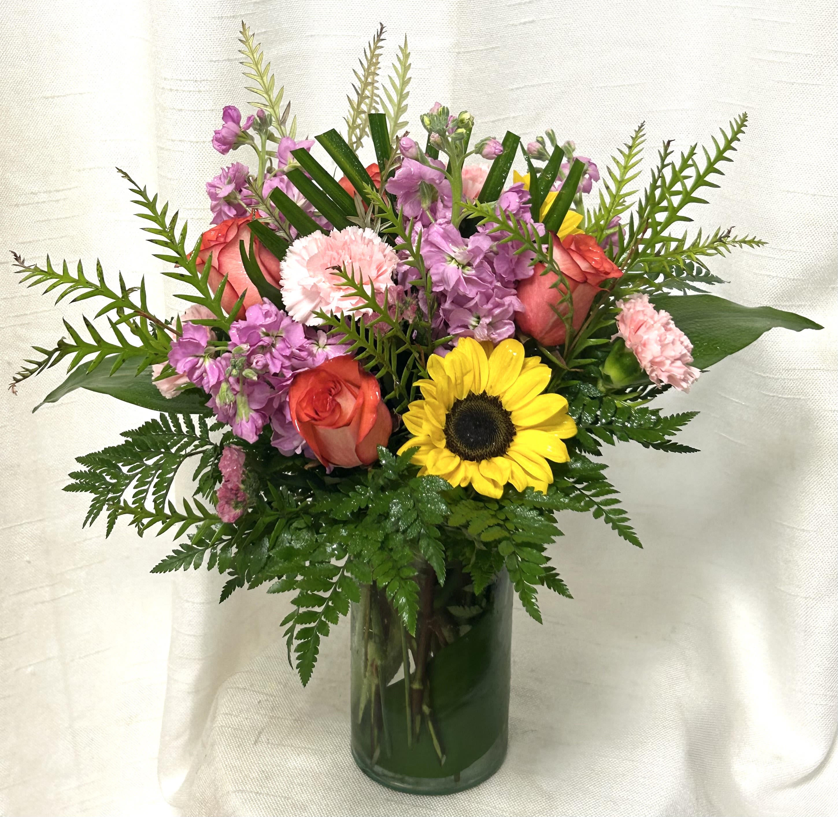 Golden Pathway (BB) - Step onto the vibrant and enchanting &quot;Golden Pathway&quot; with this stunning flower arrangement. Inspired by the warmth of sunshine and the beauty of nature, this bouquet features bright and cheerful sunflowers, delicate pink stock, lovely pink carnations, and captivating orange roses.