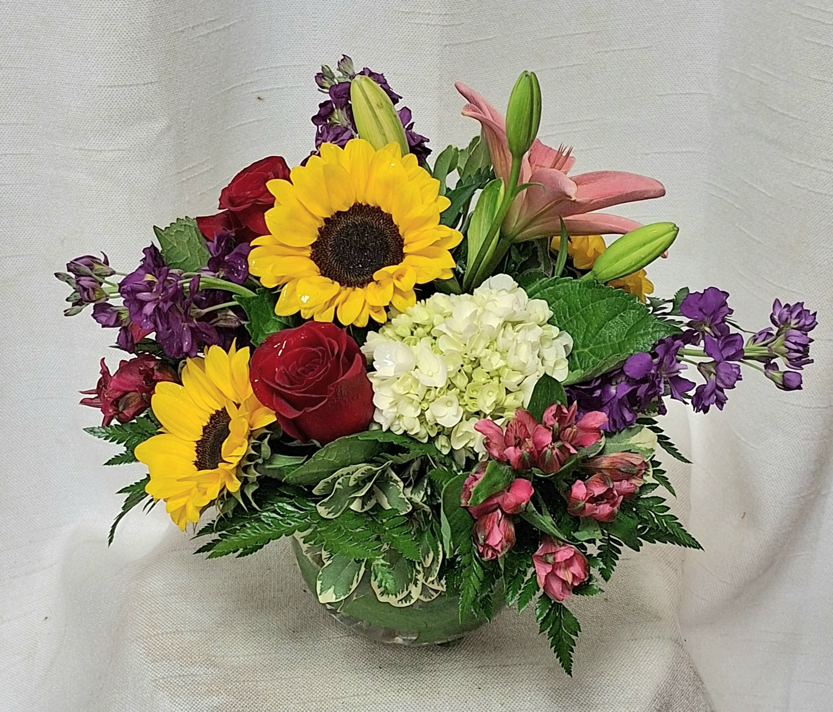 Rise And Shine (BB) - A mix of beautiful florals in a leafed lined glass container, perfect for any occasion! 