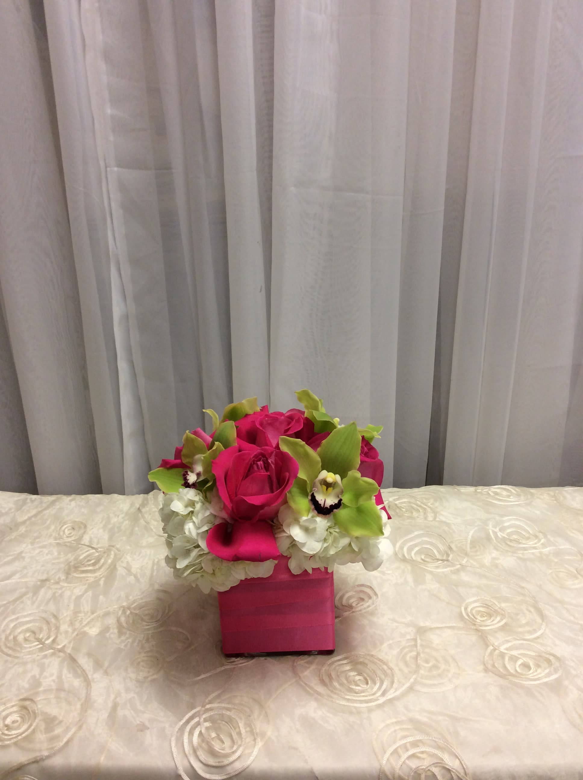 ._ Bright Mini Pave ._ Bright Mini Pave - Roses, cymbidium orchids, and hydrangeas in a ribbon wrapped square glass vase.