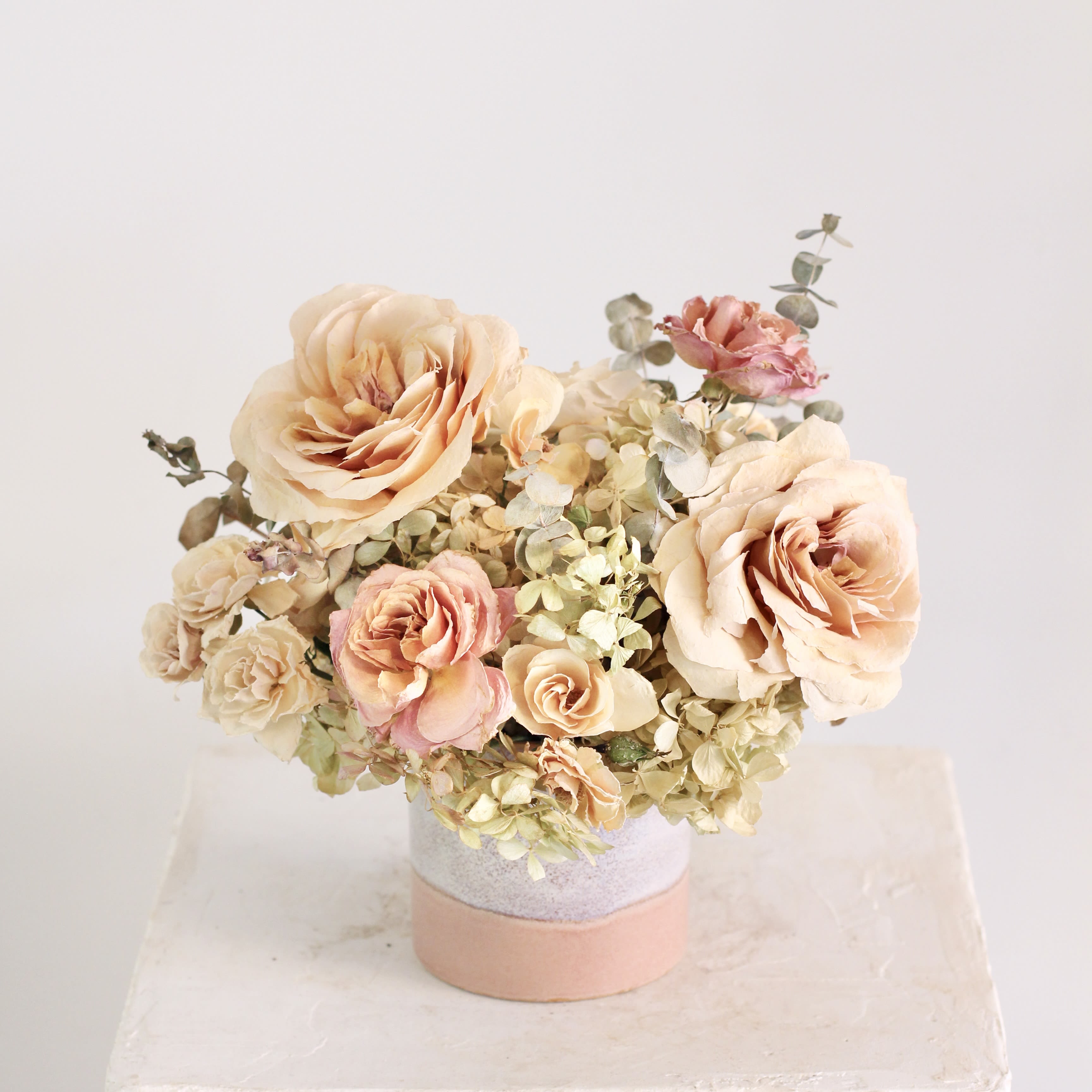 &quot;Rosette&quot; Dried Floral Arrangement - The Rosette centerpiece is a romantic dried floral arrangement that exudes timeless charm. Featuring preserved roses, spray roses, pee-gee hydrangea, and eucalyptus. Arranged in dusty rose, blush, and soft plum container, this everlasting arrangement blends classic beauty with an ethereal, modern touch. Perfect for gifting or adding a graceful accent to your space.