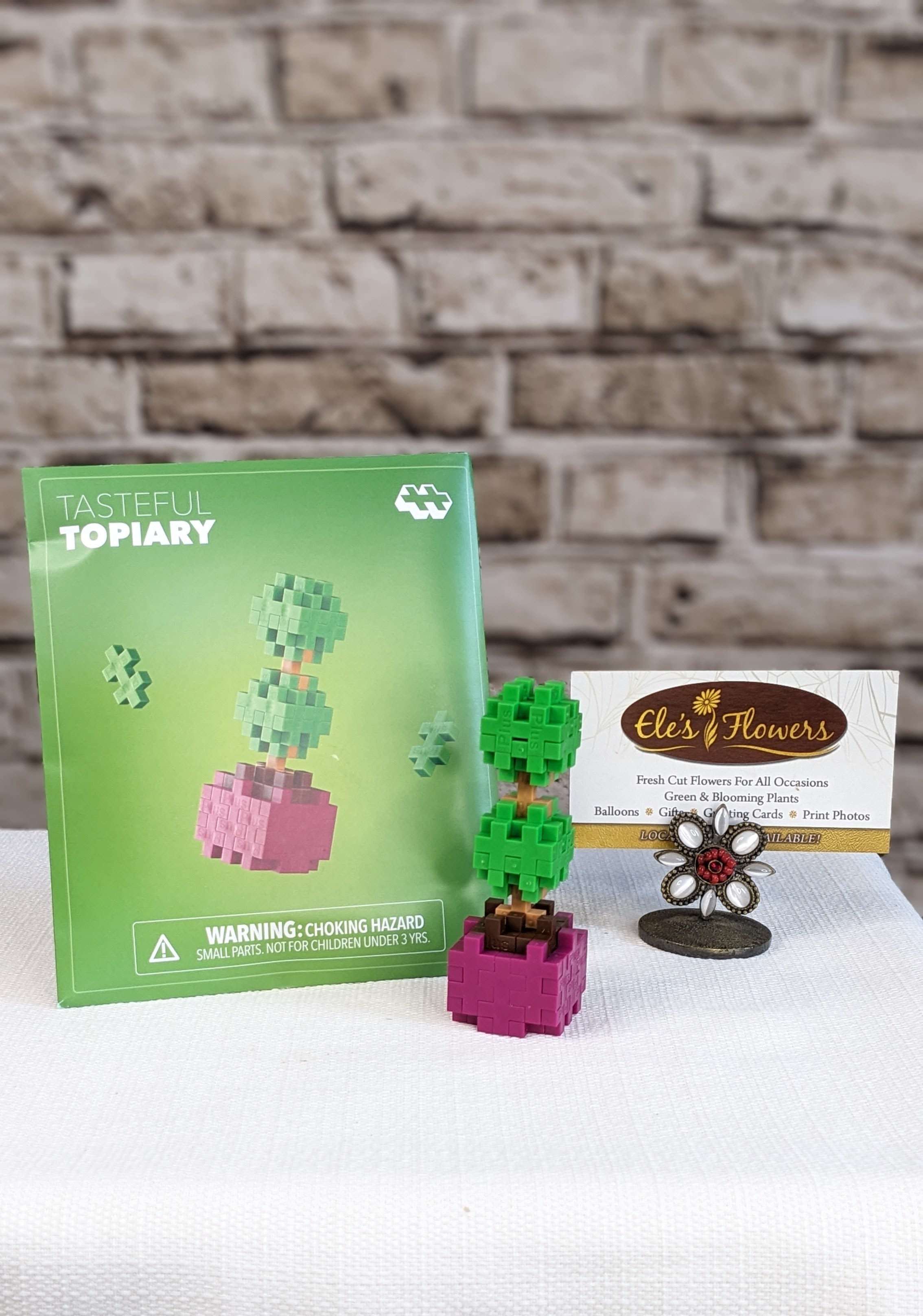 Tasteful Topiary - Plus Plus - Shape your imagination into something spectacular with this elegant Tasteful Topiary in rich shades of brown, apple, camel, and mulberry. Simple, fun, and delightfully refined, this nature‑inspired project is perfect for sparking imaginative play and hands‑on creativity. Just open, build, and watch your topiary take shape, no hedge clippers required!  Packaged like a charming springtime seed packet, it’s ideal for on‑the‑go fun, party favors, or a thoughtful little gift. Each pack includes a themed mat so your topiary can stand tall and stylish on display...green thumbs optional.  Suggested for ages 5+