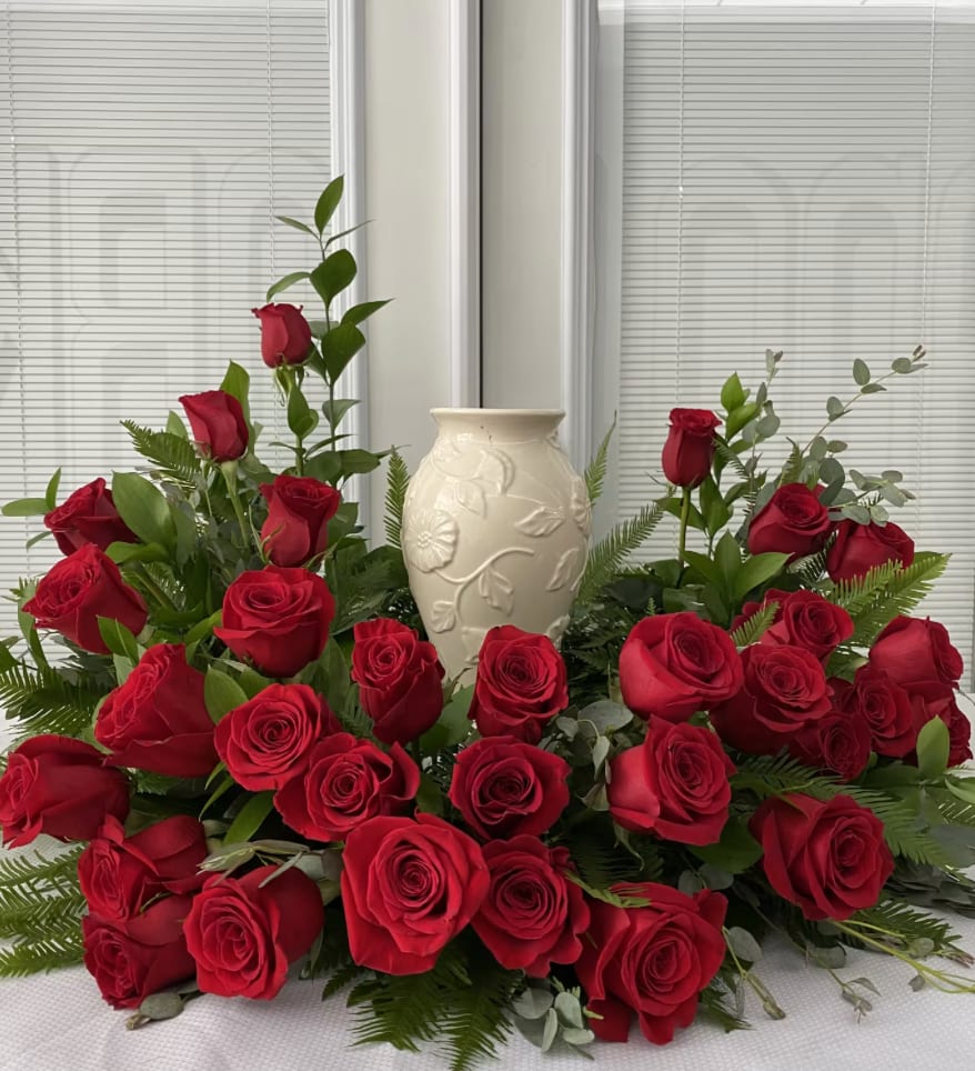 Forever In Our Hearts Forever In Our Hearts - A dignified tribute, this arrangement is adorned with a lush bed of classic red roses, symbolizing eternal love and profound remembrance. Nestled among fresh greenery and accented with tender buds, the roses gently embrace a central, creating a serene and reverent display. Designed to honor a cherished soul with beauty, passion, and respect, this arrangement speaks a silent promise: you are forever loved, never forgotten.