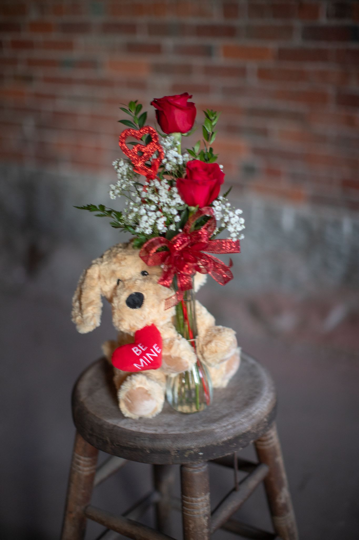Puppy Love, Be mine - A perfect Valentine's day duo! A fun fluffy stuffy with fresh flowers. A lavender infused Warmies plush doll of a puppy and &quot;Be Mine,&quot; heart hugs the base of a budvase style arrangement. Warmies can be heated in the microwave to release the lavender essence and be used as a soothing warming pad for comfort. Please call us with specific rose color requests during holiday week. It may be designer's discretion during high volume times. Limited quantity.