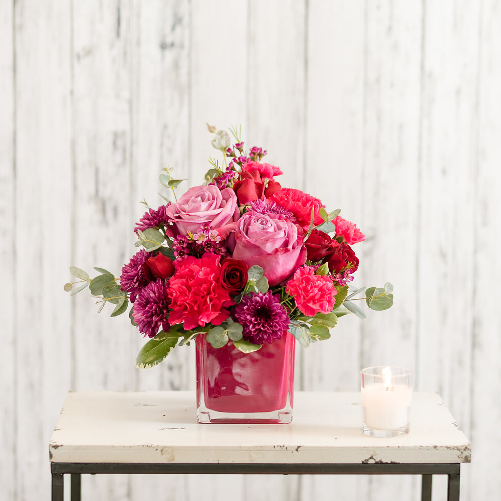 Beloved - Romantic blooms in magenta, lavender and red are classically arranged in a modern cube vase. Perfect for an end table or desk!   Approximate Size: 11&quot; H x 9&quot; W