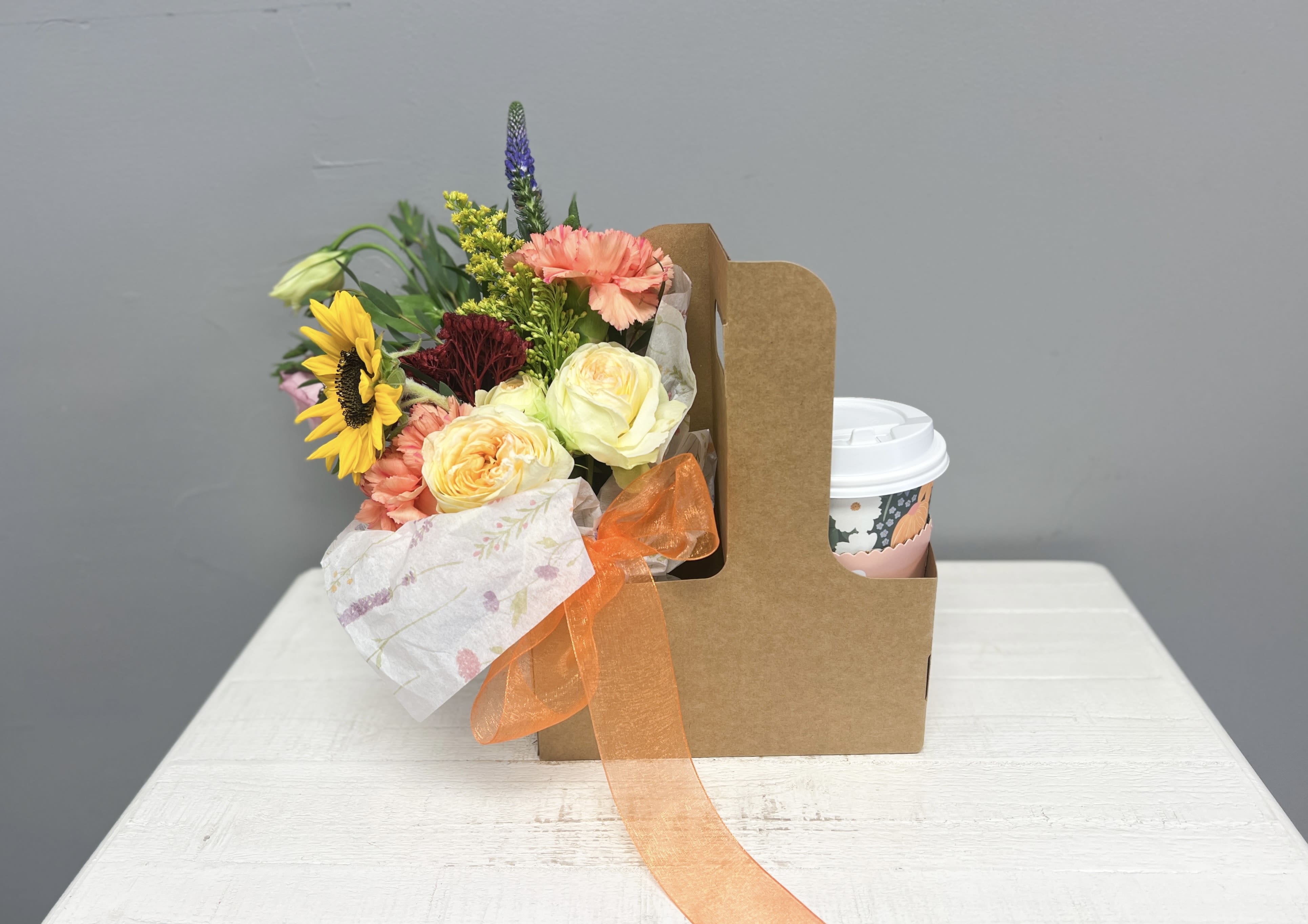 Autumn Grace Caddy - Send a thoughtful touch of warmth and encouragement with our Autumn Grace Caddy — the perfect blend of cozy vibes and heartfelt care.  Each kraft caddy includes: 	•	A hand-tied bouquet of seasonal fresh florals (hydrated with a water source to stay vibrant) 	•	A warm beverage in a charming to-go cup 	•	A curated selection of self-care items such as honey, herbal tea, shower steamer, under-eye gels, and more 	•	A rotating encouragement card (designs may vary) to uplift and inspire  Beautifully packaged and ready to brighten anyone’s day — from “thinking of you” to birthdays or seasonal surprises. 