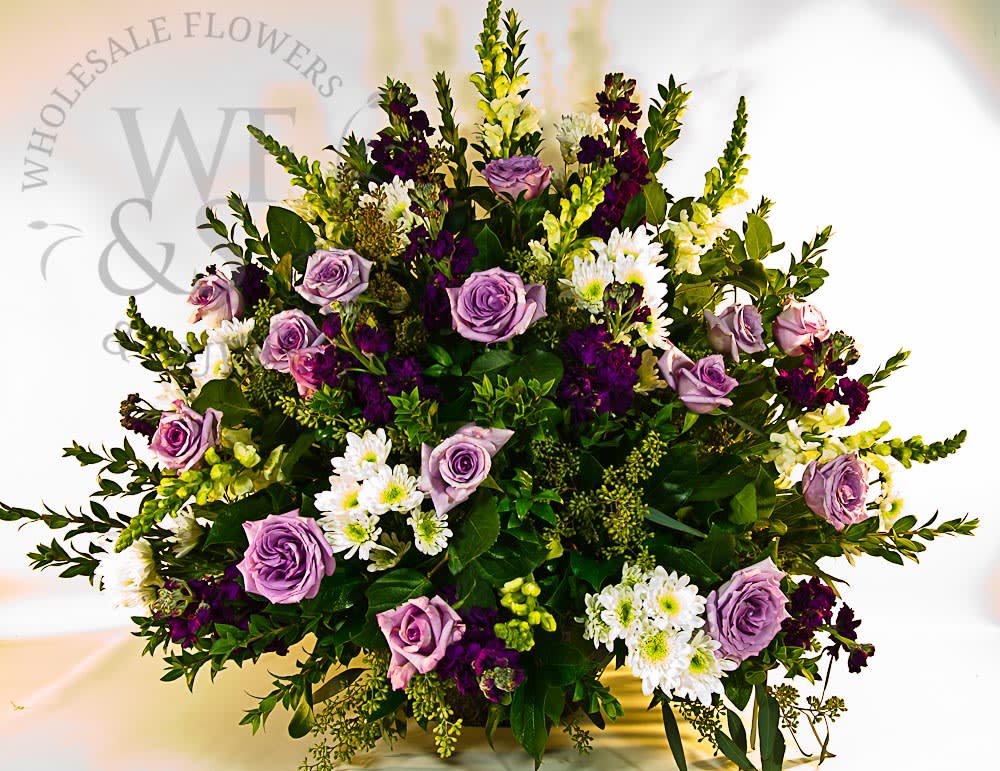 LAVENDER BLISS ON E SIDED ALTAR ARrANGMENT  - OUR LAVENDER BLISS ONE SIDED ALTAR ARRANGEMENT comes with snap dragon, stock, pom pom cushion, roses &amp; other seasonal flowers and greenery !!  
