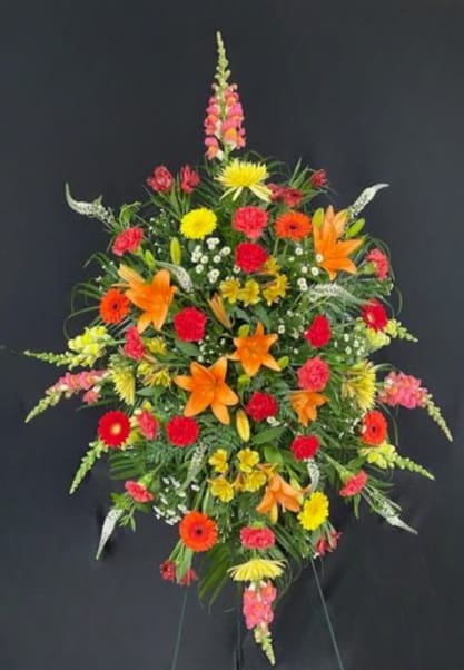 Setting Sun - Celebrate a truly special life with this beautiful standing spray of vibrant yellows, oranges, and reds. Includes roses, lilies, gerbera daisies, fuji mums, snap dragons, veronica, alstroemeria and mums. Arrangement is mounted on a 54&quot; standing easel for prominent display at funeral services.