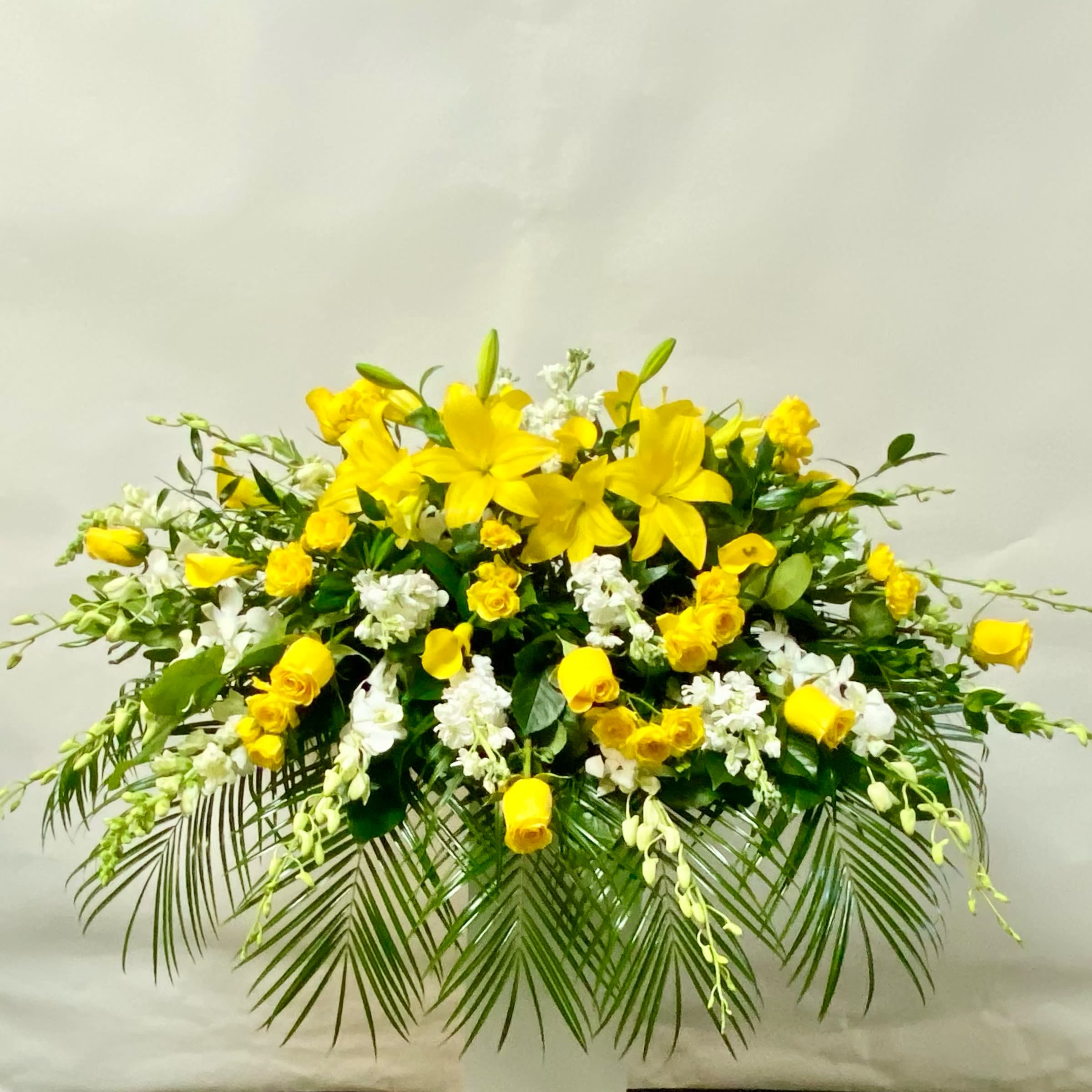 Sunshine Gardens Casket Spray - This Casket Spray Includes Yellow Roses, Yellow Lilies, Yellow Spray Roses, Mini Yellow Callas, White Dendrobium Orchids, White Stock and White Snapdragons. Or as Similar as Possible. 