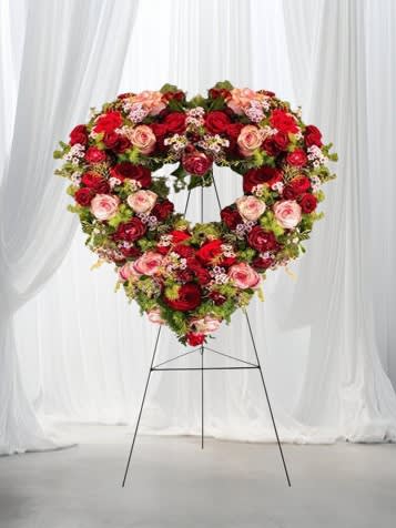 Always in Our Hearts - This majestic heart-shaped tribute is a heartfelt way to express your love. It is a lush design with an abundance of red and pink roses, various types of greenery, and other complementary flowers to complete the look.  This design can be customized in a solid or other colors. Please call the shop for customization.