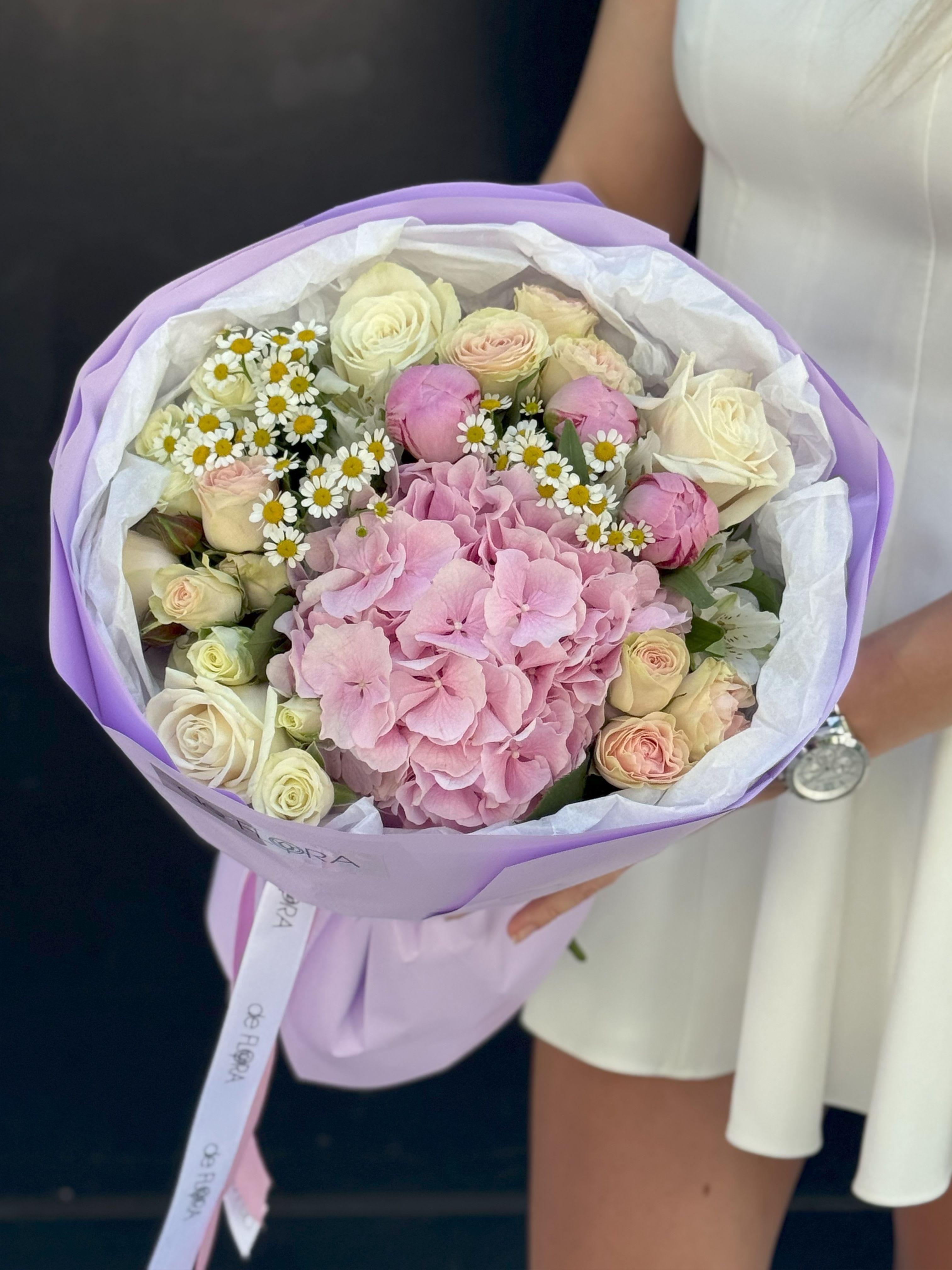 Sweet Serenity - A gentle and dreamy bouquet that whispers elegance. Soft blush hydrangeas take center stage, surrounded by creamy ivory and pale pink roses, delicate chamomile blooms, and lush seasonal greenery. Wrapped in lavender paper with a satin ribbon, Sweet Serenity is the perfect gift for expressing tenderness, love, or gratitude — ideal for birthdays, romantic gestures, or simply brightening someone’s day.