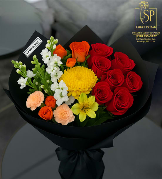 Midnight Radiance - Flowers by SweetPetals – Brooklyn presents Midnight Radiance, a luxurious statement piece from our Luxury Collection. This breathtaking arrangement blends the timeless romance of velvety red roses with the golden glow of chrysanthemum, cheerful orange spray roses, delicate peach carnations, crisp white stock, and sunny yellow alstroemeria — each bloom hand-selected for its exceptional freshness, vivid color, and flawless beauty.  Wrapped in elegant matte black luxury paper and tied with a sleek satin ribbon, Midnight Radiance exudes sophistication, charm, and modern elegance. Perfect for anniversaries, birthdays, grand celebrations, or as an unforgettable gesture “just because,” this bouquet is designed to leave a lasting impression.  With free same-day delivery across Brooklyn, SweetPetals ensures your Midnight Radiance bouquet arrives fresh, stunning, and ready to captivate.   SweetPetals – Sweeten Every Occasion 