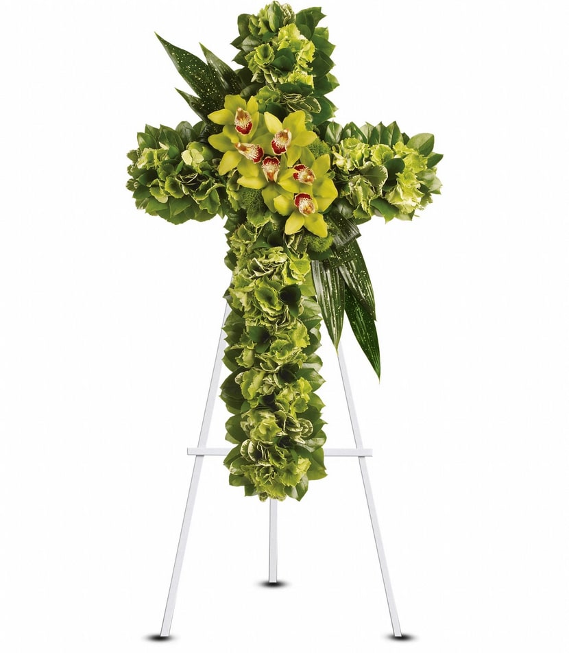 Comforting Thoughts Floral Cross - This dramatic floral cross embodies a powerful symbol of renewal. Light greens contrast with dark to make a striking standing spray. It includes flowers such as green cymbidium orchids and hydrangea, along with variegated greenery. Some flowers and shades of flower color may vary based on the time of year.  Approximately 22″ W x 35″   NOT AVAILABLE FOR SAME DAY DELIVERY