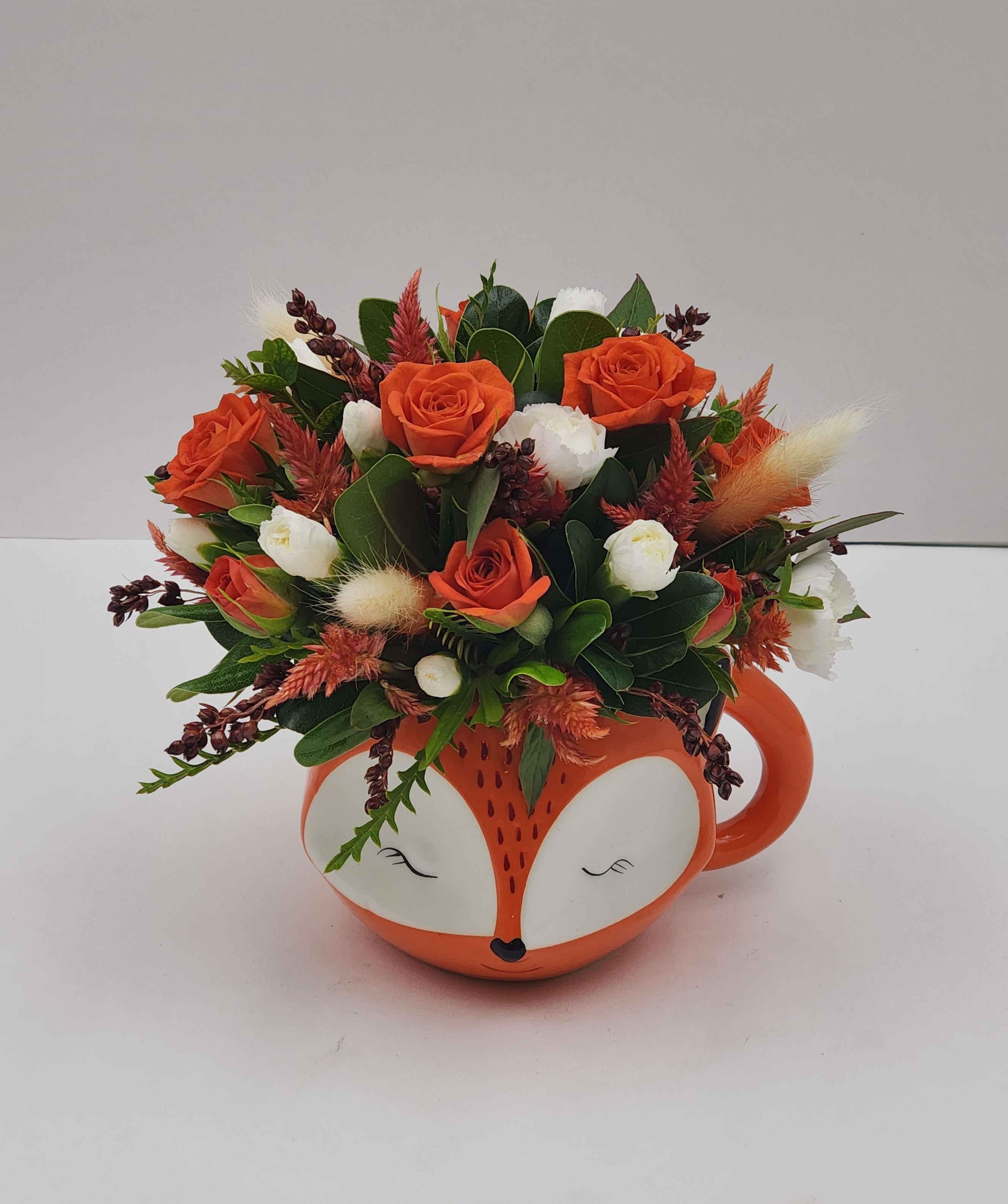 Fox in the Hole - This unique and adorable arrangement is made in a keepsake fox mug that includes spray roses, bunny tail and more! This arrangement is made to been seen from all angles and is approximately 8.5&quot; tall by 7.5&quot; wide. 