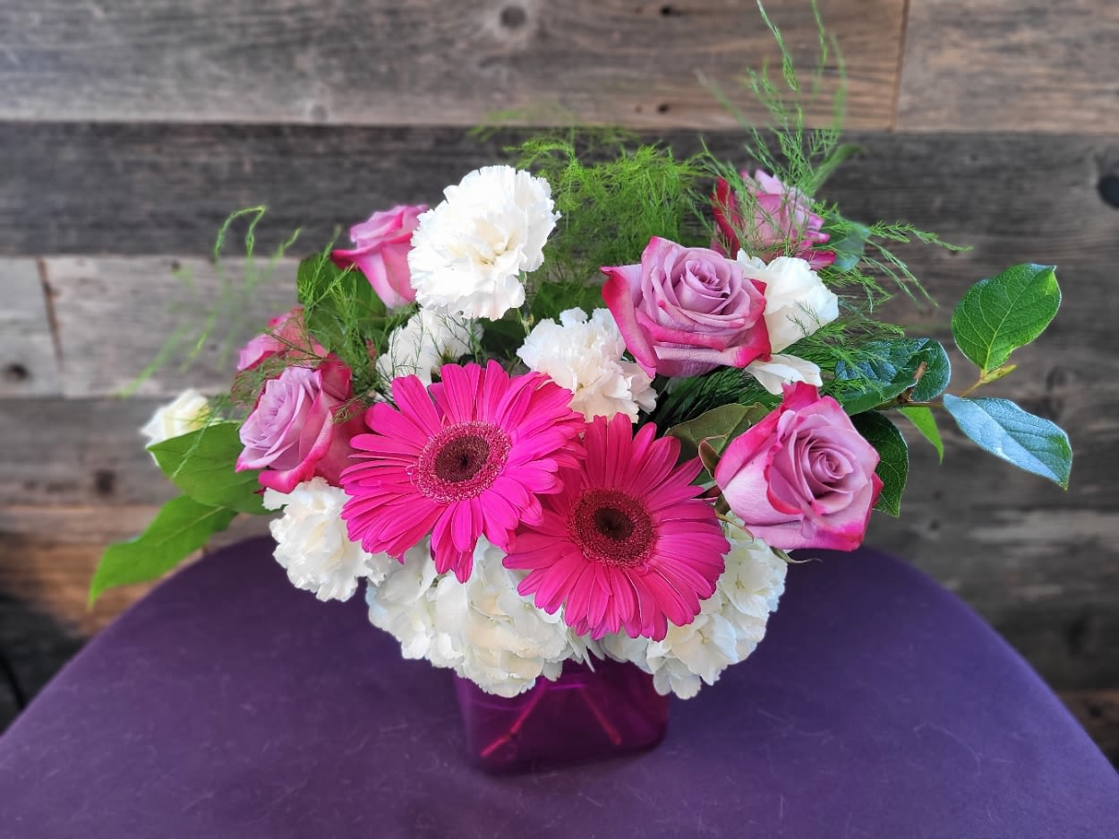 Walk in the Meadow Walk in the Meadow - Bold yet graceful, this arrangement features radiant hot pink gerbera daisies, lavender-pink roses, and fluffy white hydrangeas and carnations, all gathered in a magenta glass cube. It’s a confident blend of color and texture—perfect for birthdays, celebrations, or just saying, “You’re fabulous.”