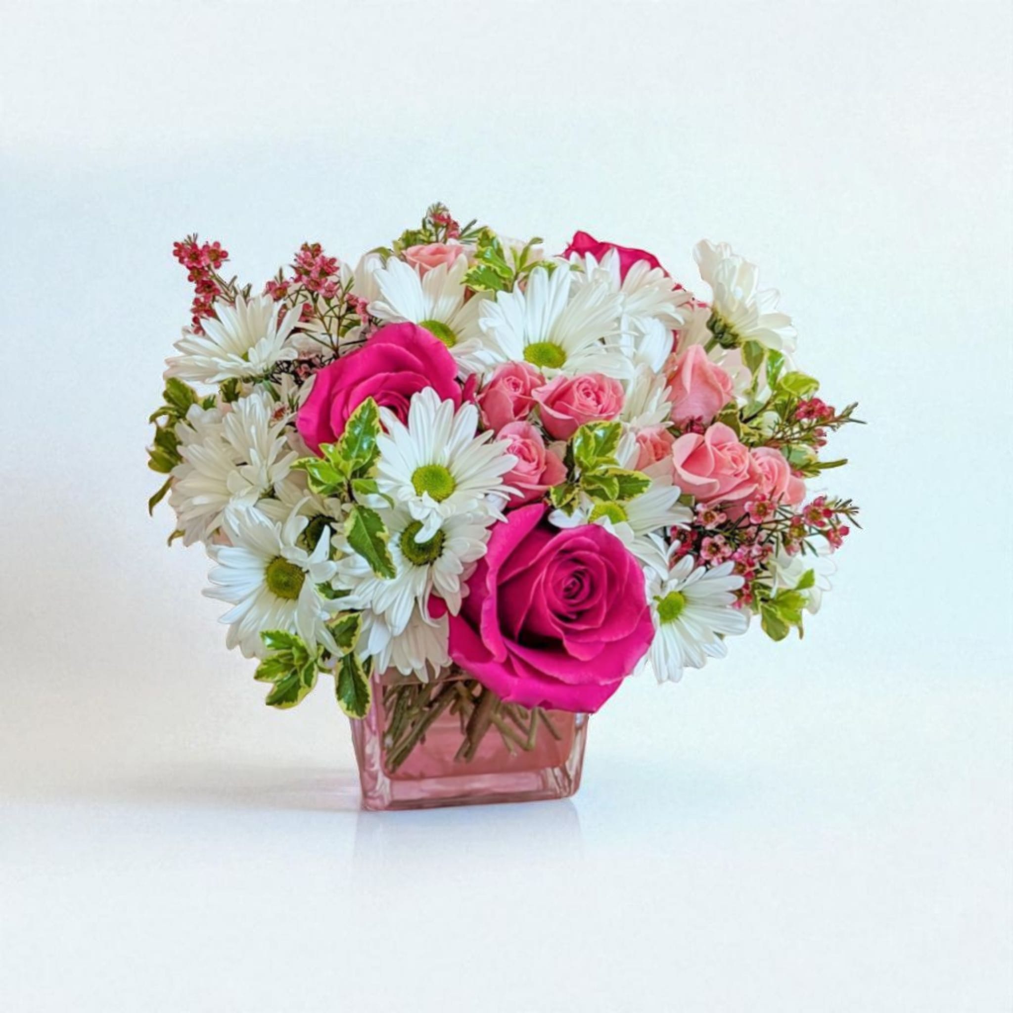 Blush & Bloom Blush & Bloom - A cheerful blend of bright fuchsia roses, soft pink spray roses, and fresh white daisies creates a bouquet full of charm and joy. Accented with delicate greenery and seasonal blooms, this arrangement is perfect for celebrating life’s sweet moments — from birthdays to heartfelt “just because” surprises. Handcrafted in a pink glass cube vase, it brings a touch of romance and freshness to any space.