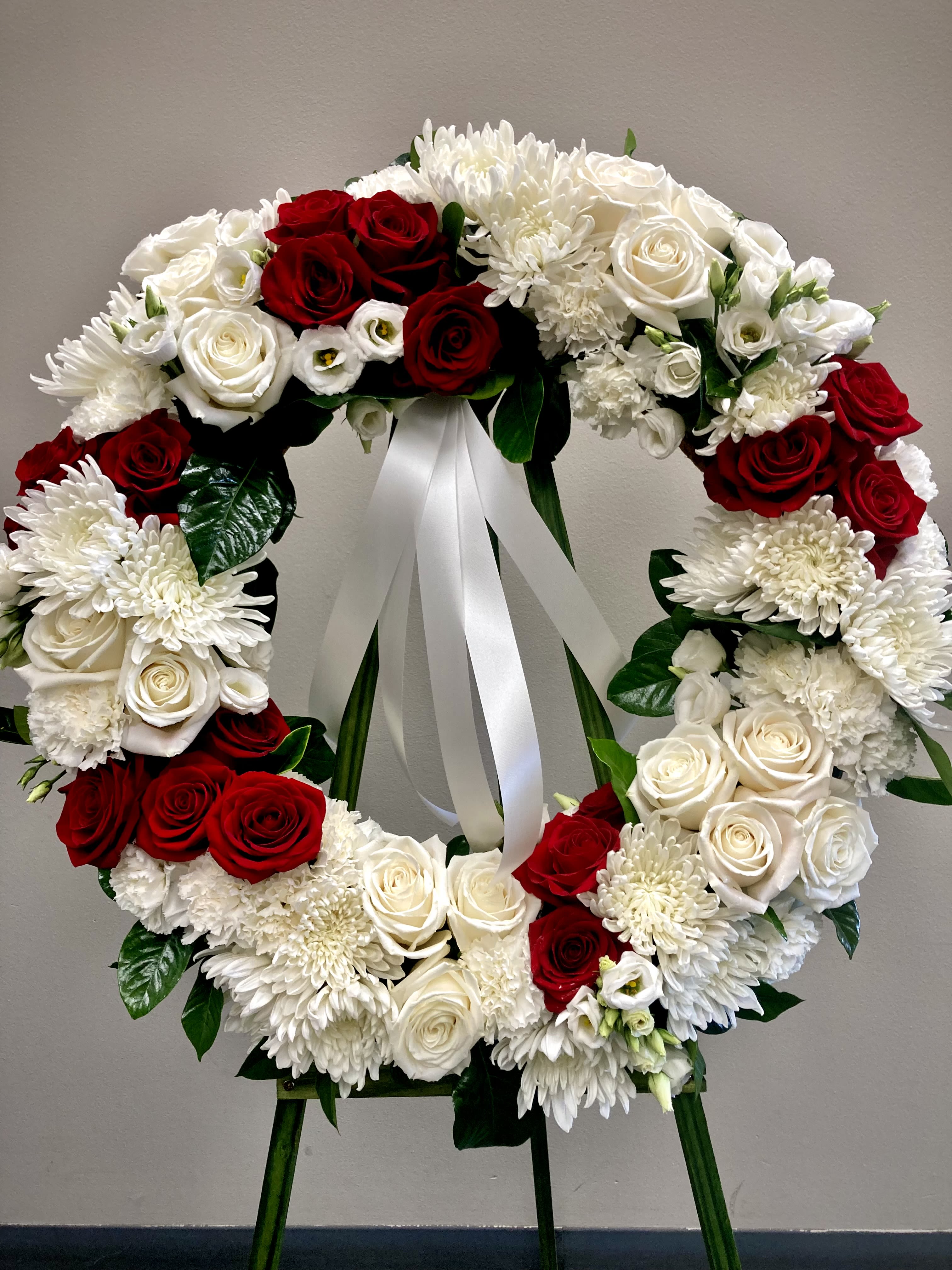 Wreath of Hope Wreath of Hope - Red and white roses with lisianthus, hydrangea adorn our classic wreath presented on an easel. A display of hope and memory.