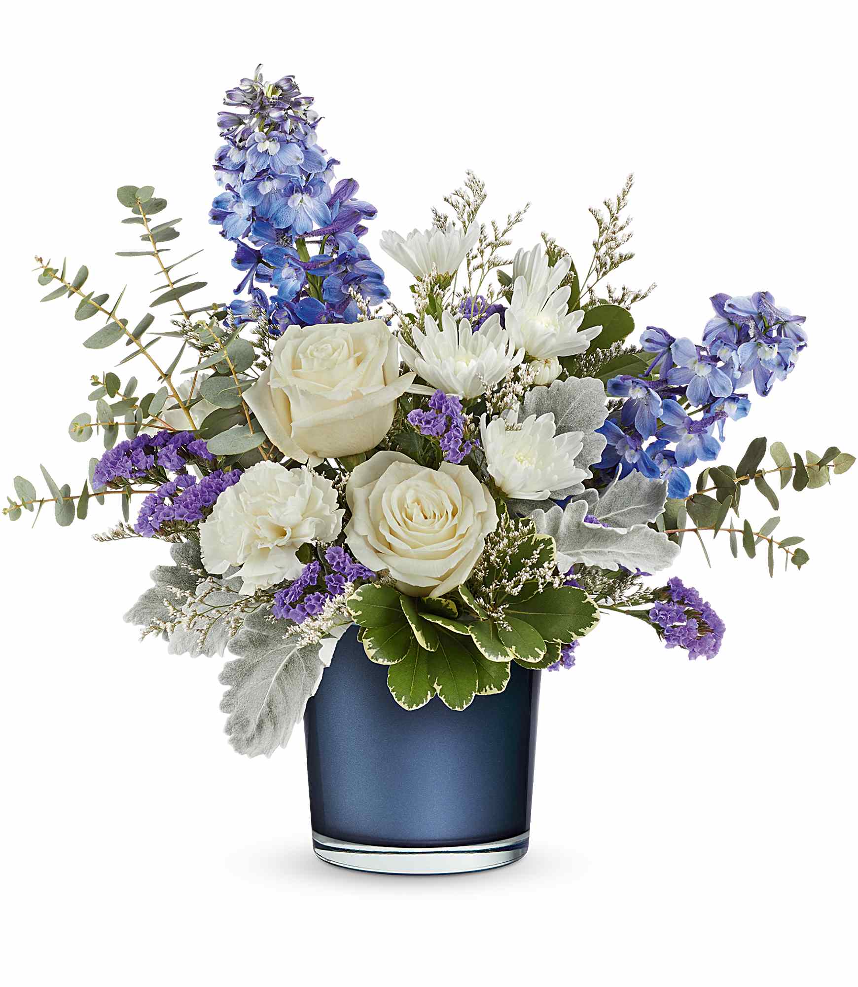 Teleflora's Sapphire Bliss Bouquet - Tranquil blues! This lovely crème rose bouquet resembles fluffy white clouds against a clear blue sky, elegantly paired with a sapphire blue glass vase that shimmers with a pearlescent finish. This arrangement features crème roses, blue delphinium, white carnations, white cushion spray chrysanthemums, blue sinuata statice, and purple limonium, accented with dusty miller, spiral eucalyptus, and variegated pittosporum. It is beautifully delivered in Teleflora's Polished Gem Vase.
