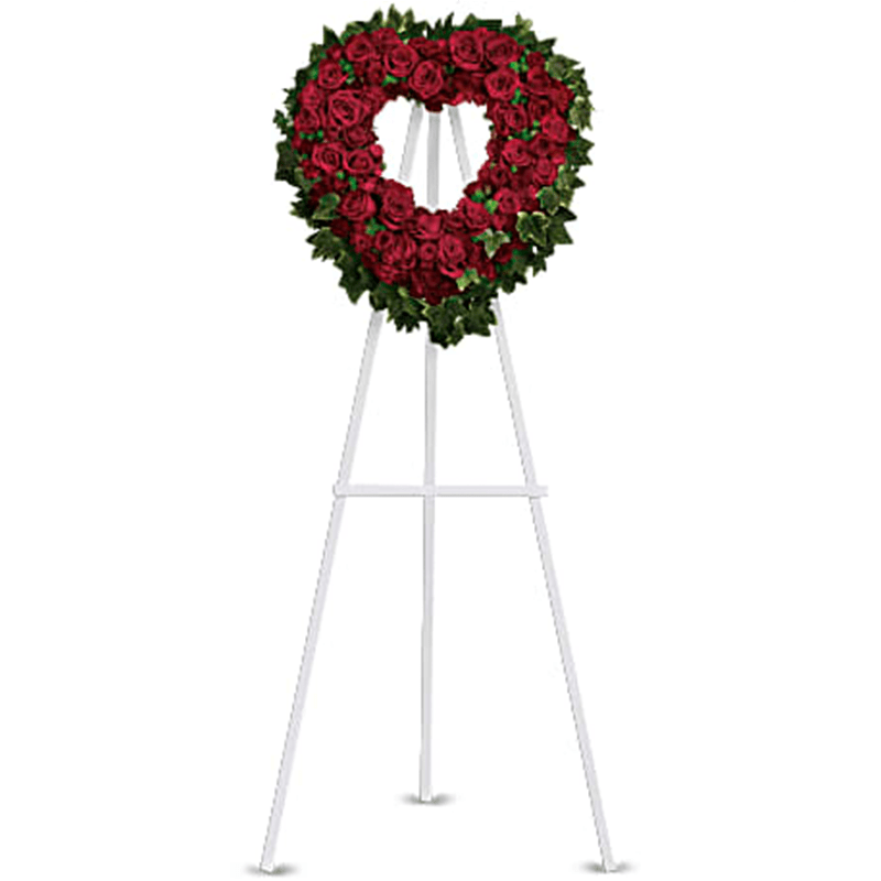 The Blessed Heart Standing Spray - Make a strong, stylish statement of love with this beautiful heart-shaped wreath. Presented on a funeral easel, the rich red rose sympathy arrangement is a lovely standing spray to place on the altar or by the entrance to the service. Red roses and carnations are accented with ming fern and variegated ivy on an open heart-shaped wreath. Presented on a traditional wire easel for ease of placement. Orientation: One-Sided