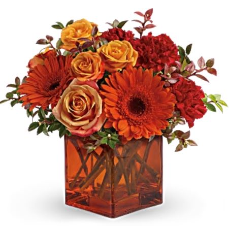 Sunrise Sunset - Celebrate the wonder of a new day with warm, golden flowers. A modern orange glass vase is the foundation of this stunning, sun-bright bouquet that energizes any occasion. •Orange gerbera daisies, orange roses and red mini carnations are accented with a spray of red huckleberry in an orange cube vase. •Orientation: One-Sided 