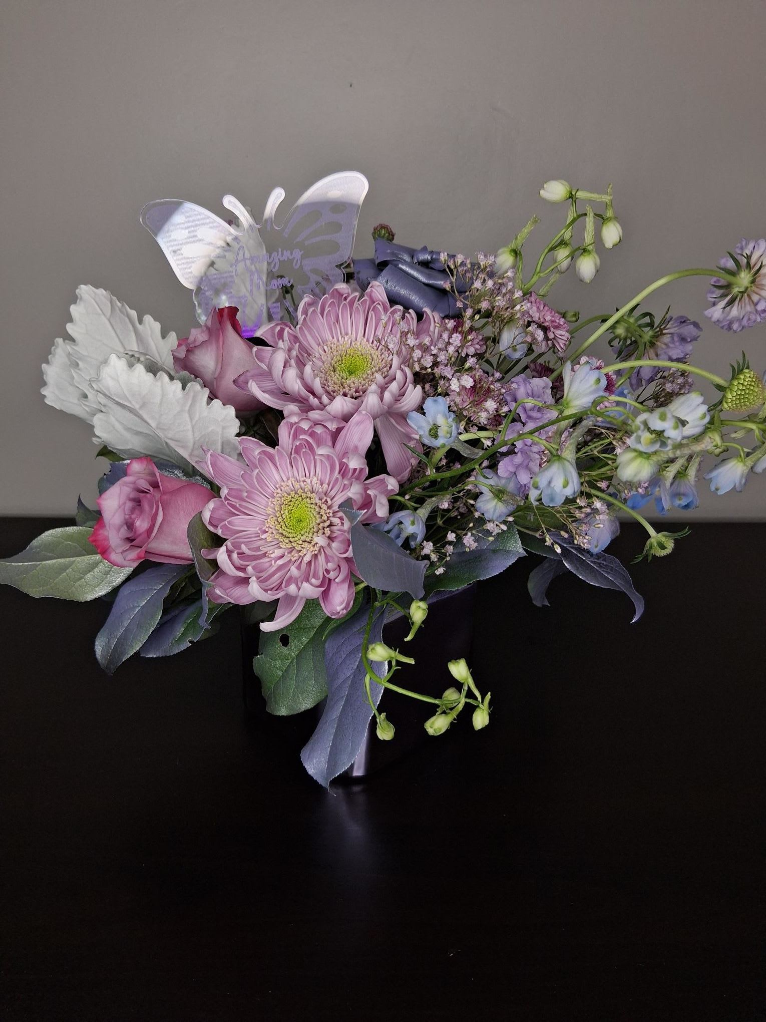 Metallic Fantastic - It all started with a vase. A metallic lavender so light it reminded me of clouds, to enhance the color of the vase we included tinted greenery and an aspidistra rose in the same shade of metallic lavender. Topped off with a touch of light blue and silver dusty miller. 