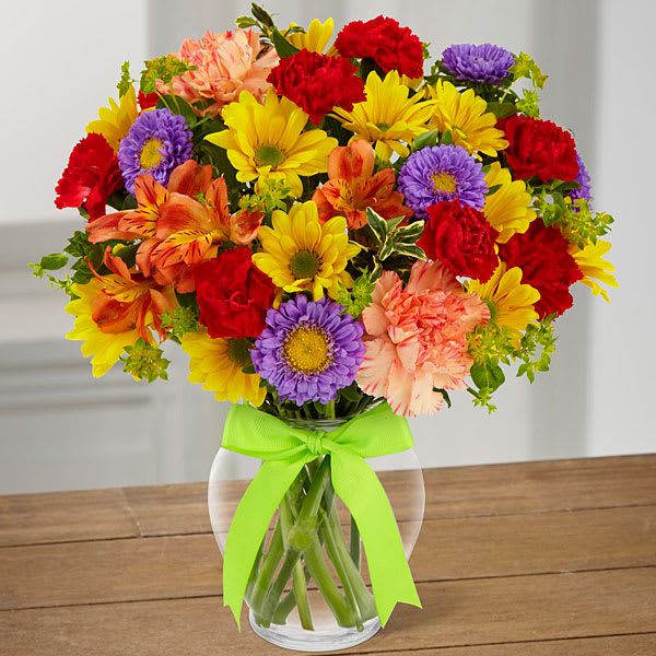 The Light & Lovely Bouquet The Light & Lovely Bouquet - All the frills and every color under the sun this fresh flower arrangement is ready to brighten your recipient's day! Yellow daisies, orange Peruvian Lilies, lavender matsumoto asters, orange carnations, and red mini carnations are accented with bupleurum and lush greens to create a fascinating display. Presented in a clear glass vase tied with a lime green ribbon at the neck this flower bouquet is set to send your warmest wishes in celebration of their birthday to express your thanks and gratitude or to tell your recipient to get well soon! GOOD bouquet includes 8 stems. Approx. 12"H x 10"W. BETTER bouquet includes 13 stems. Approx. 13"H x 11"W. BEST bouquet includes 17 stems. Approx. 16"H x 14"W.