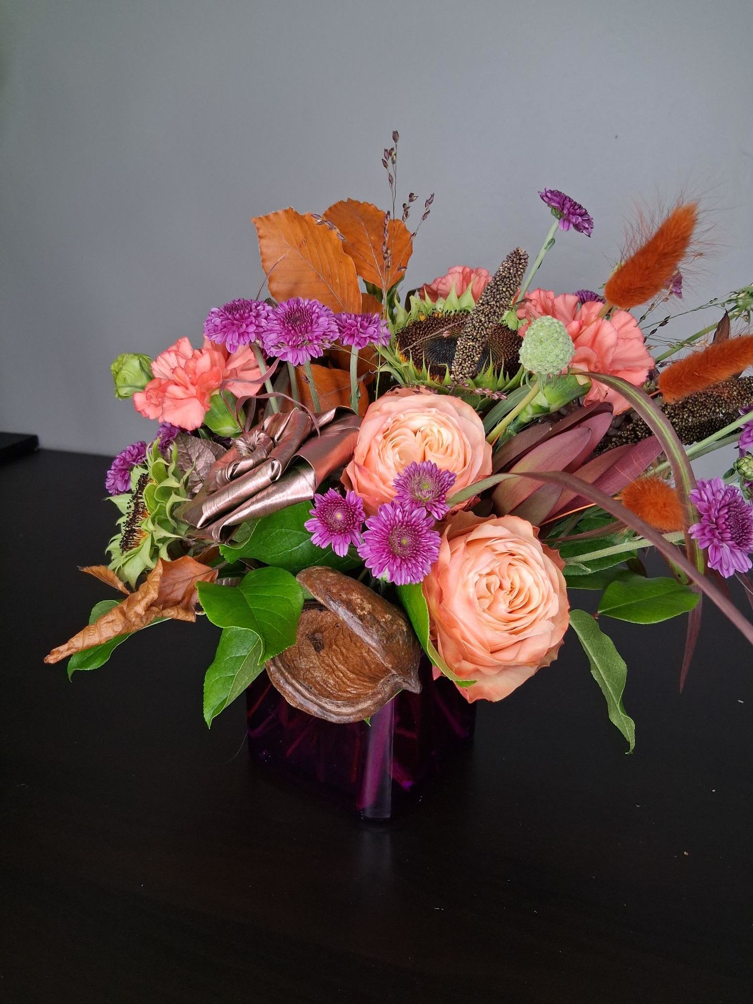 Autumn Bliss - Simple charming gathering of orange, purple, rose gold and rusts featuring Van Gogh style sunflowers, millets, grasses and bunny tails. Fall leaves and deconstructed carnations lead us into the fall season. 