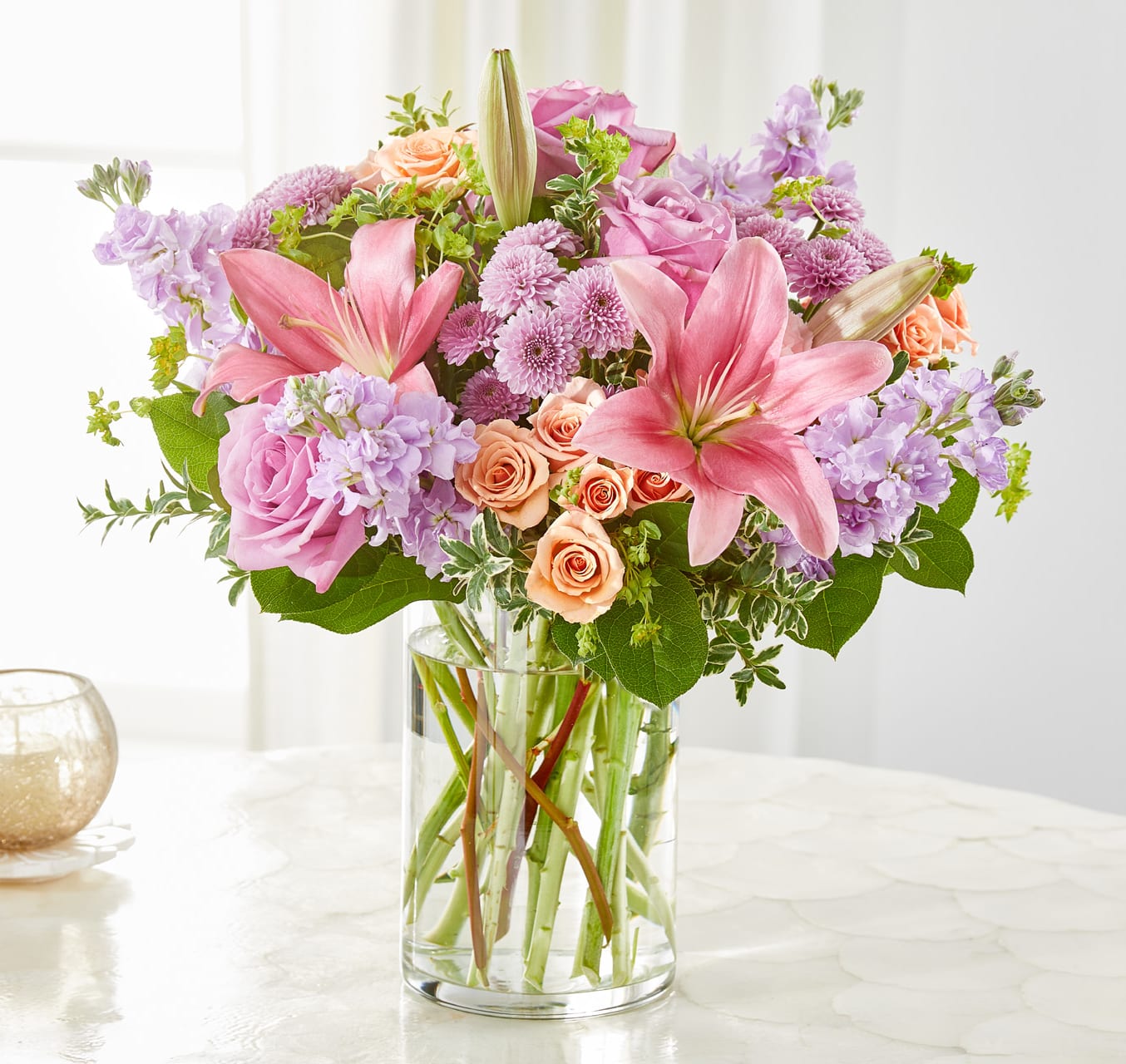 Resilience Bouquet Resilience Bouquet - A symbol of strength and beauty, the Resilience Bouquet is designed to uplift the spirit with its harmonious blend of blooms. Lavender stock, roses, and button pompons pair gracefully with peach spray roses, pink carnations, and lilies to create a bouquet that radiates hope and comfort. Perfect for expressing support, celebrating milestones, or honoring meaningful moments, this arrangement speaks to resilience in every petal. Approximately 17"h x 17"w