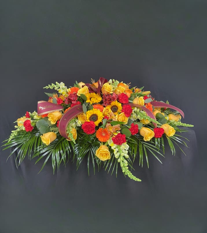Fall Mixed Floral Casket Spray Fall Mixed Floral Casket Spray - A mix of seasonal flowers in shades of reds, oranges, yellows centered around vibrant sunflowers. Price includes up to 4 custom printed ribbons.