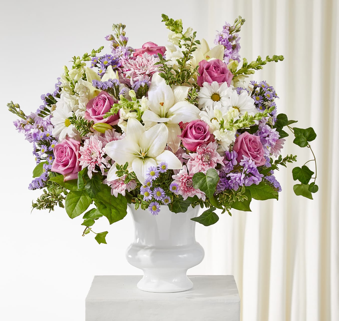 Remarkable Life Arrangement Remarkable Life Arrangement - Celebrate a life beautifully lived with the Remarkable Life Arrangement. Lavender roses, stock, cushion pompons, and statice are gracefully blended with white snapdragons, lilies, and daisies, while touches of purple monte casino add depth and charm. This lush design offers a comforting tribute and a heartfelt expression of love and remembrance. Approximately 23"h x 24"w