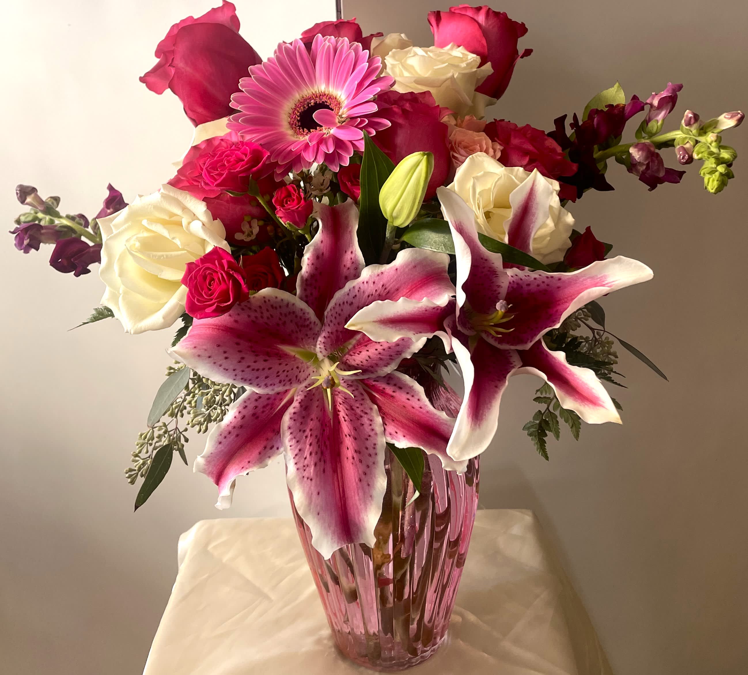 LOVE IN BLOOM LOVE IN BLOOM - GORGEOUS PREMIUM ARRANGEMENT, WITH HOT PINK AND WHITE ROSES, STARGAZER LILIES, BEAUTIFUL SNAPDRAGONS, SPRAY ROSES, PINK GERBERA DAISY, GREENS AND FILLER FLOWERS IN A PINK PREMIUM VASE.