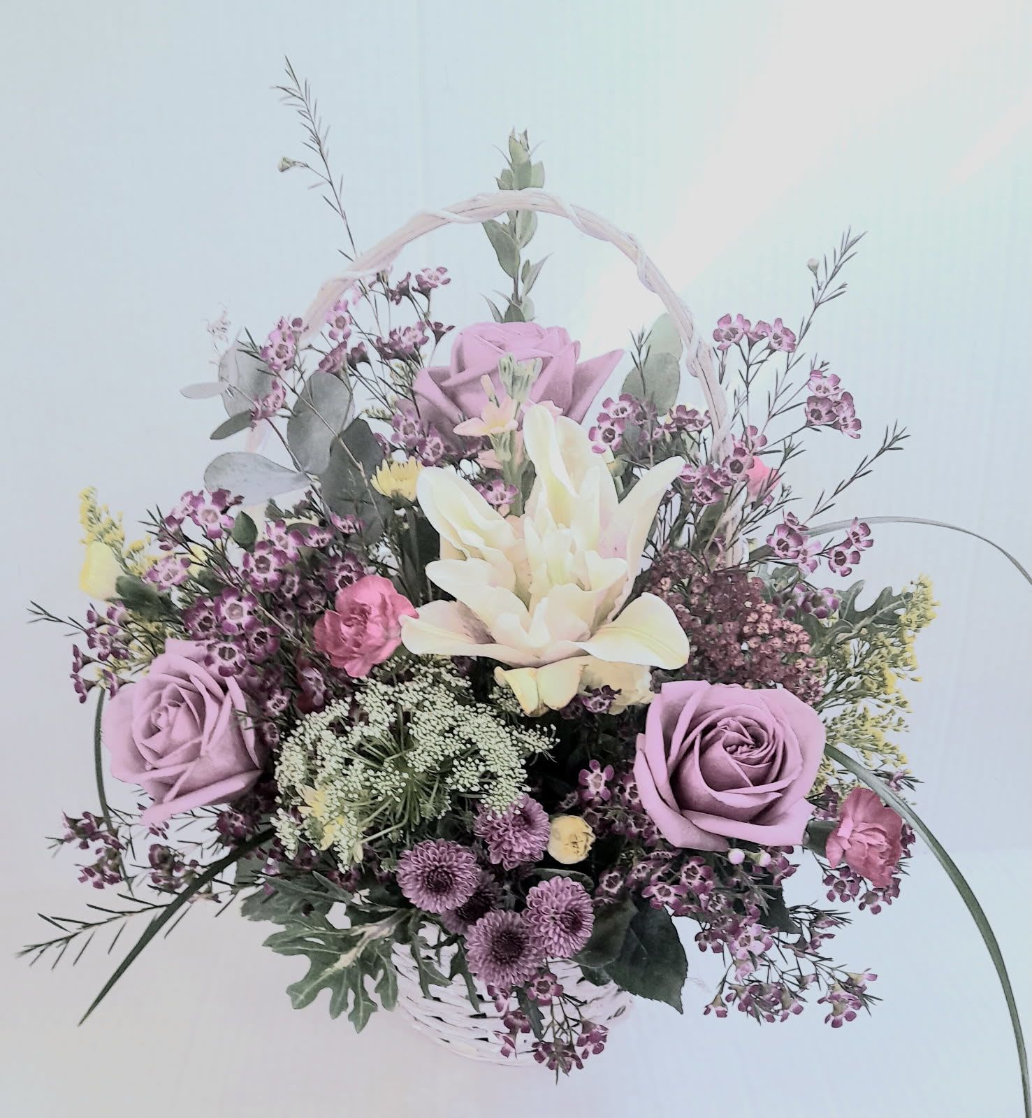 Victorian Beauty Basket - Lovely and soft, lavender roses, fragrant wax flower, lily and an assortment of flowers in a tall handle basket , is soothing and beautiful for any occasion!
