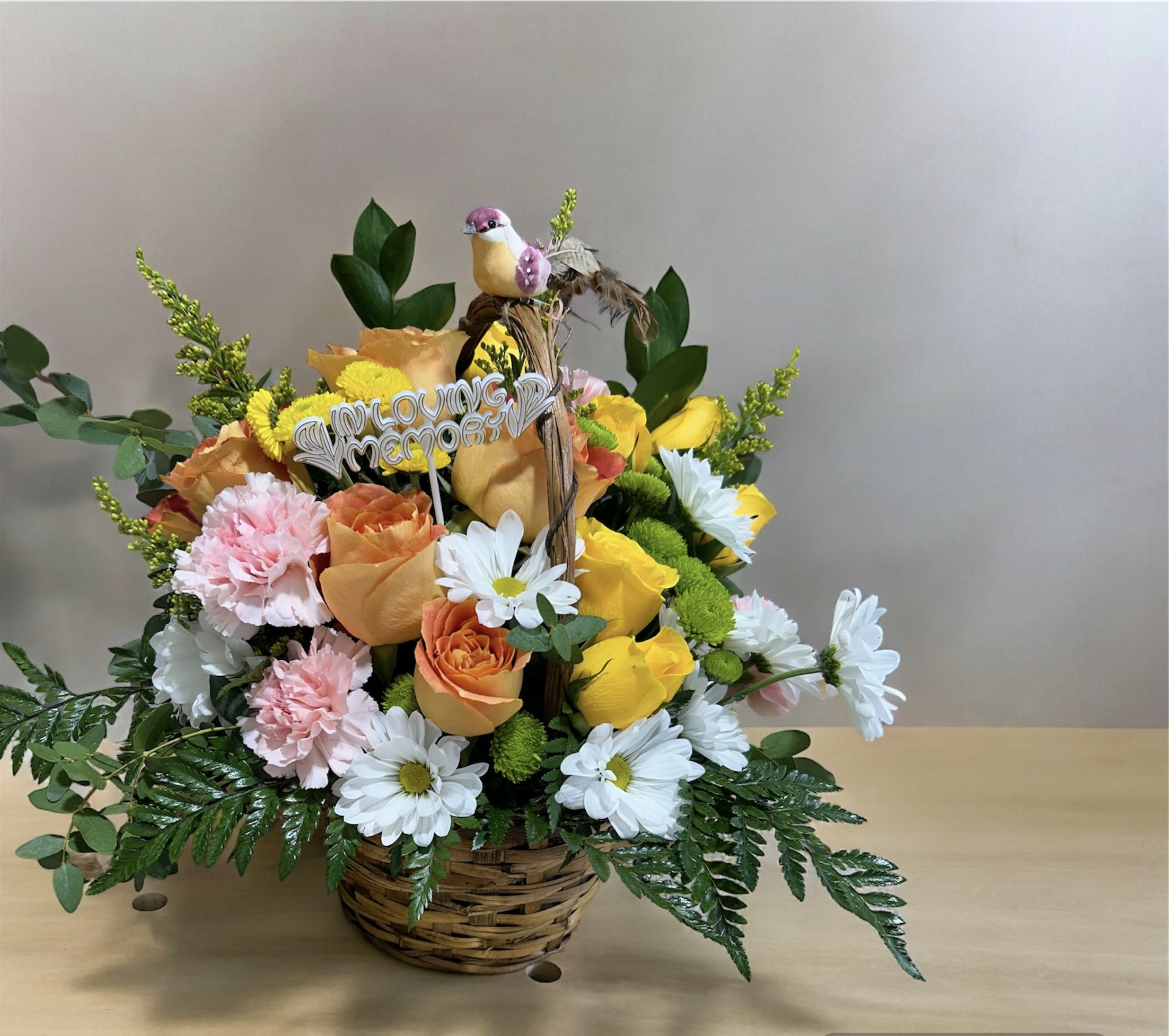 A Thoughtful Embrace - A comforting mixed flower basket featuring soft pink carnations, gentle orange and yellow roses, serene white daisies, green and yellow button mums, and delicate solidago, all accented with lush greenery. This thoughtful arrangement conveys sympathy, warmth, and heartfelt support during difficult times.