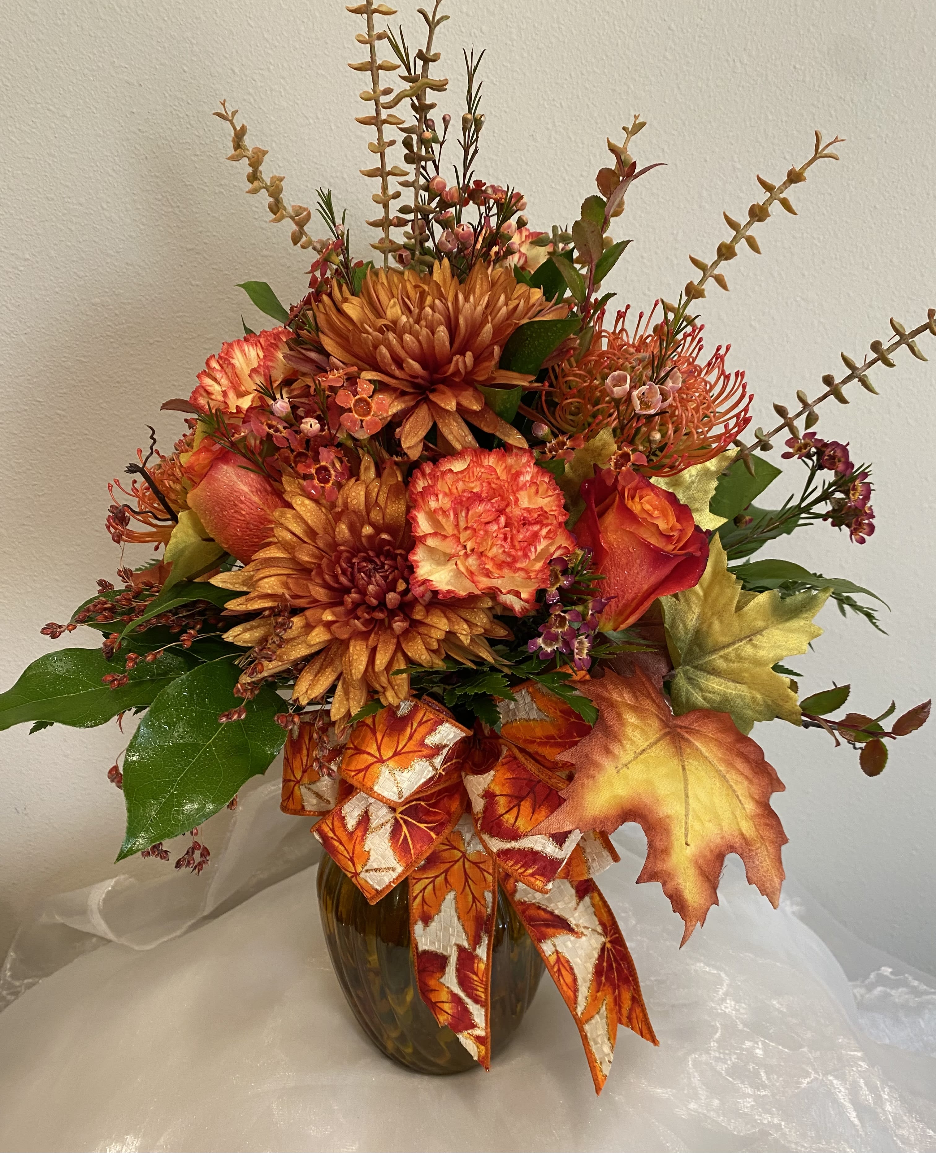 Autumn Skies - This vase arrangement has all the beautiful colors of fall. Roses, carnations, protea, cremones (big mum) and more.  Sometime substitutions happen but we will keep within the color theme and feel.