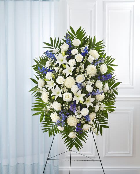 Blue & White Standing Spray Blue & White Standing Spray - Standing spray arrangement with white roses, Asiatic lilies, football mums, carnations and monte casino; blue delphinium; accented with soft, lush greenery