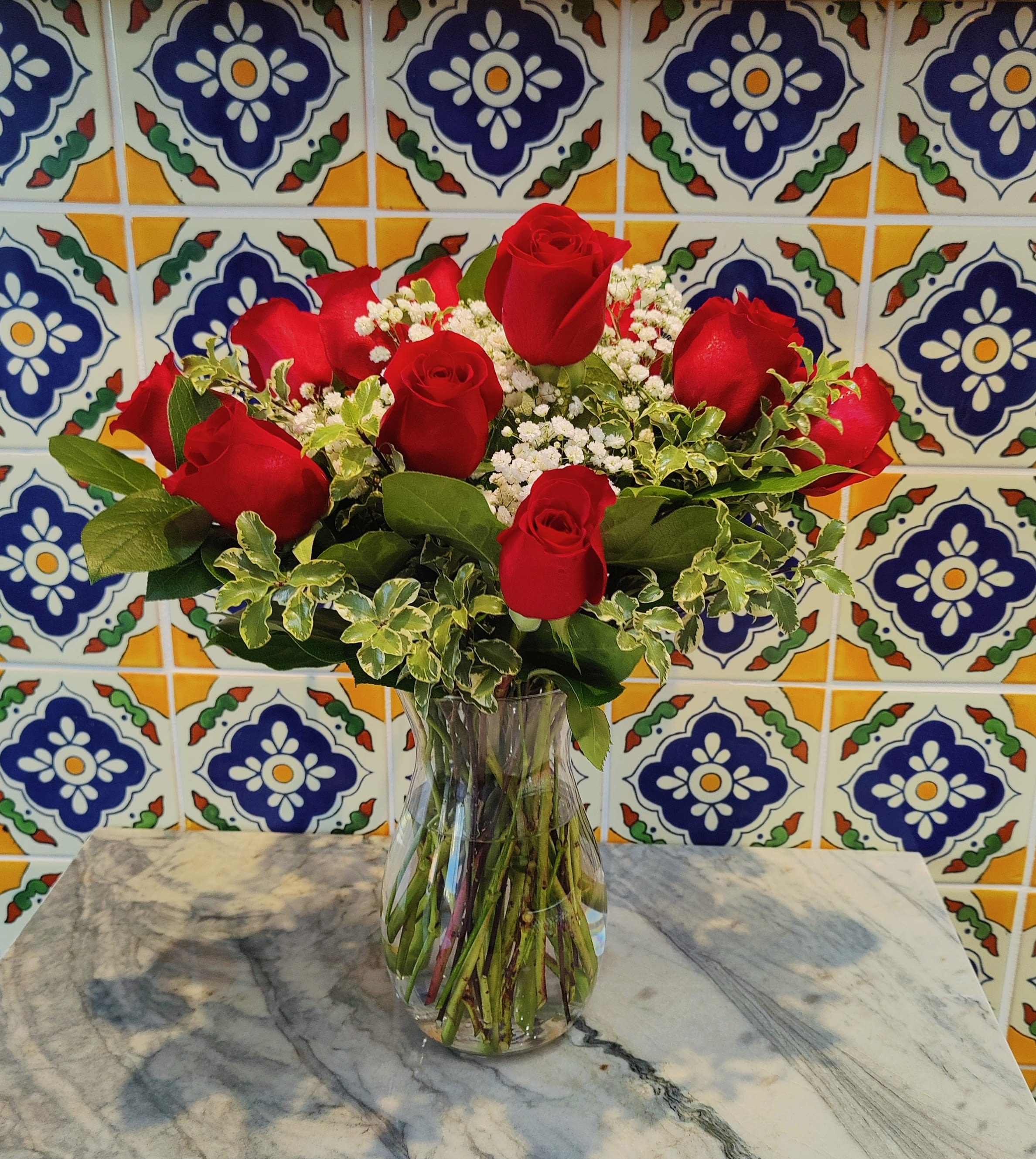 Beautiful Dozen Red Roses  - Share Joy Share flowers. Beautiful red roses accented with some seasonal fresh foliage and little filler flowers. It includes a beautiful glass vase. Medium size  Classic style arrangement  Standard size includes 12 roses Deluxe includes 18 roses 