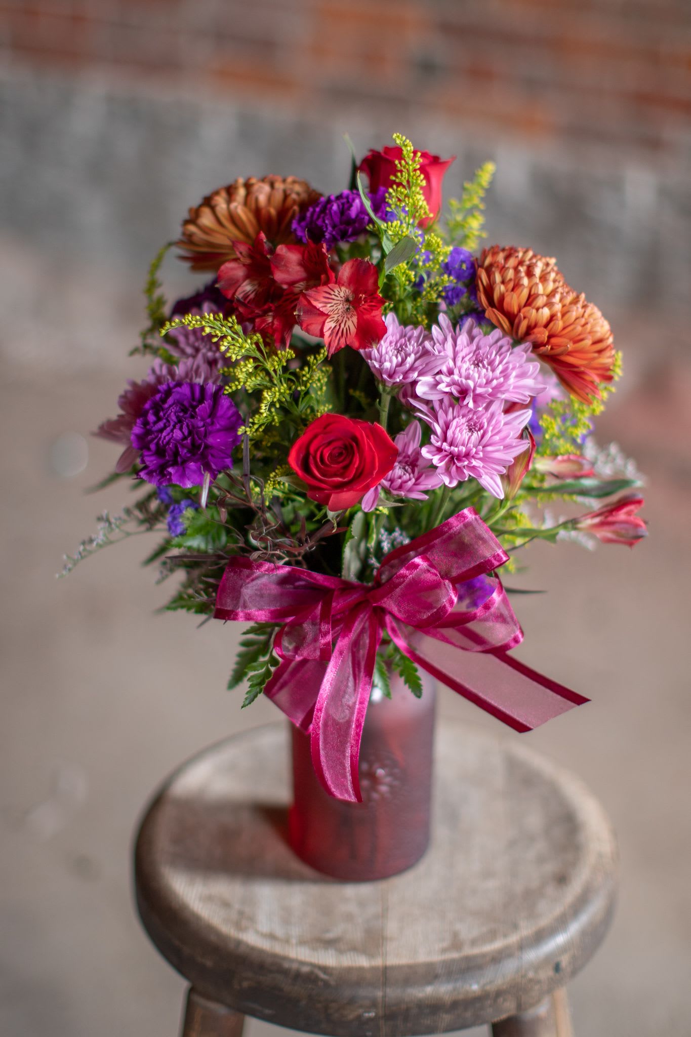 Sweater Weather - With the coming of cool crisp air we introduce our latest design in a textured jar vase. A Selection of fall floral favorites. The assortment of flowers may include roses, sunflowers, Asiatic (fragrance-free) lilies, mums, daisies and foliage and accent flowers that compliment the colors of the vase and other flowers. &quot;Sweater Weather,&quot; essentially is an autumnal version of our Garden Jam arrangement which is popular in the spring and summer months and was the inspiration for this design created by Zach. These are a wonderful host gift, or a few can e used to create a lovely table scape for Thanksgiving.