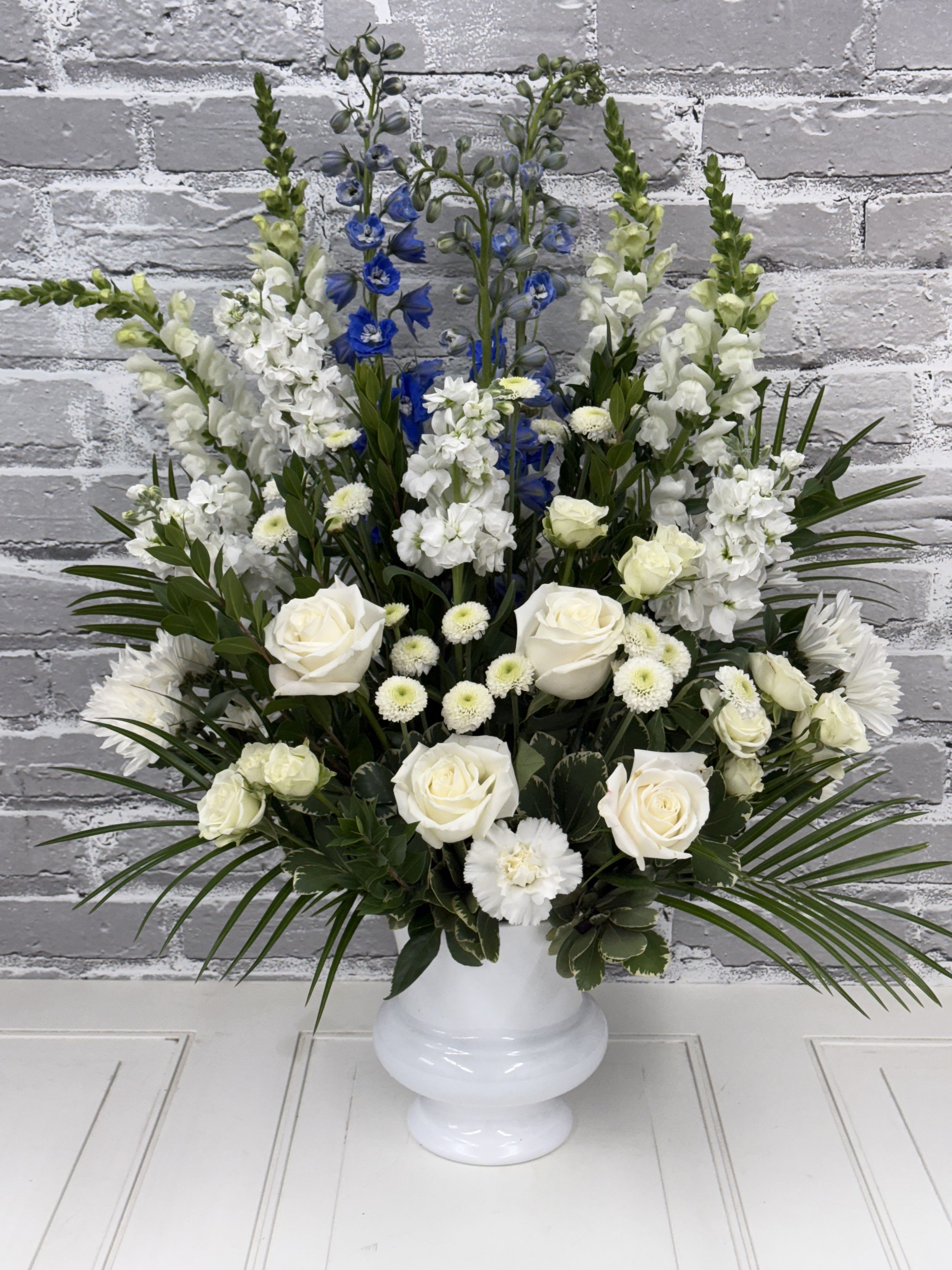 Love and Light Spray - Intended for a service at a church or funeral home, this spray of flowers in whites with a touch of blue is a perfect sentiment at a difficult time. Flowers may vary due to availability. 