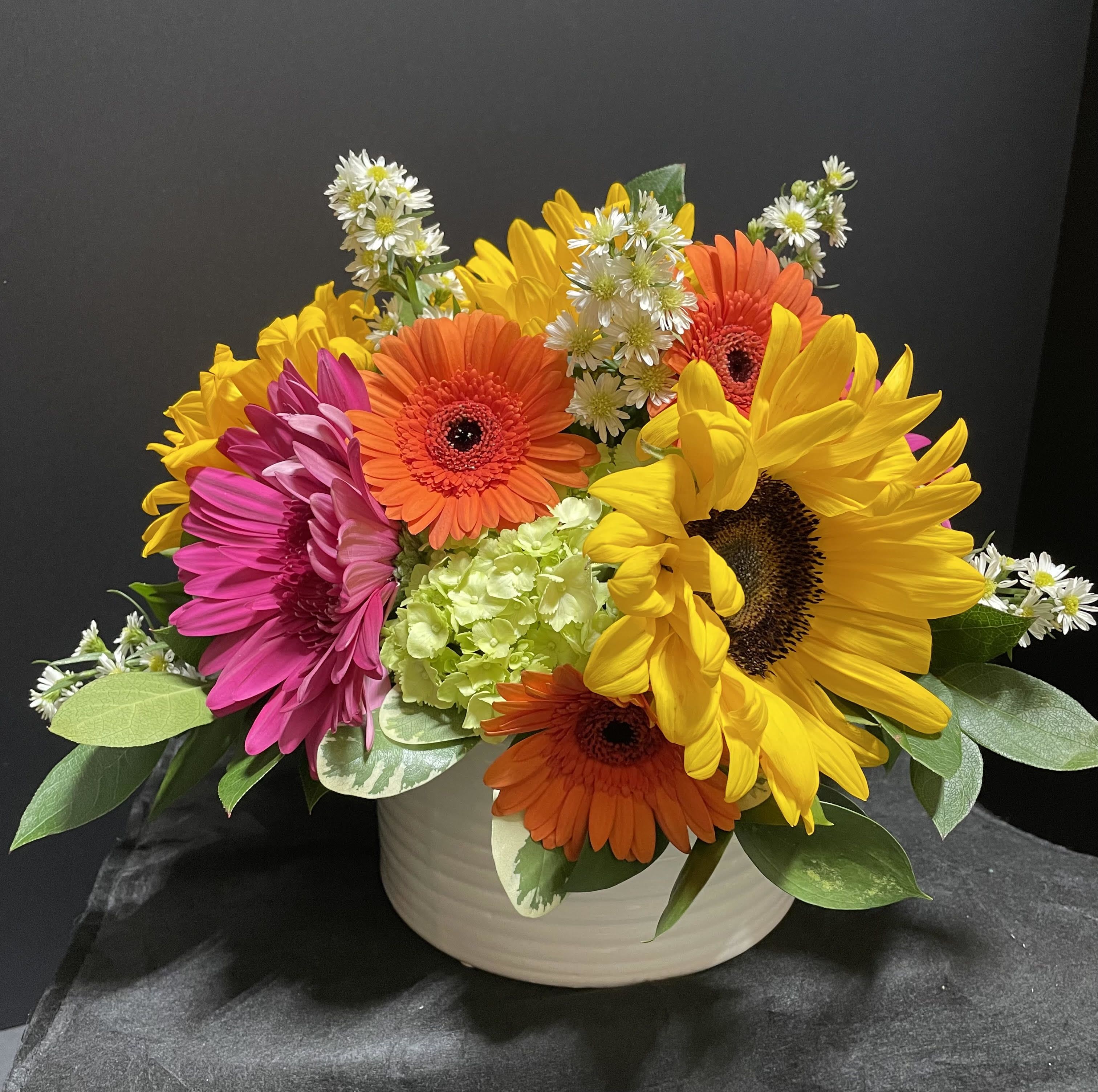 Sunflower Splash - Colorful sunflowers, gerbera daisies, hydrangeas and more in ceramic vessel. Option to put in popular wooden cube- just call and let us know!  Color variation possible- let's discuss.  Substitutions as necessary due to ever changing availability of fresh blooms.