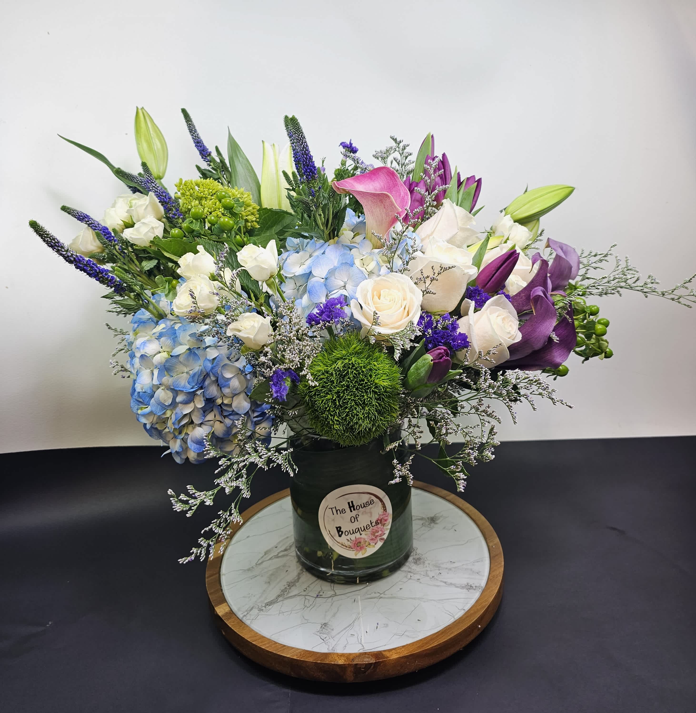 Beach House - A stunning centerpiece or gift, the Beach House bouquet will transport you to paradise with its cool and relaxing colors. Filled with hydrangea, veronica, roses, green ball, calla lily, hypericum, and fillers. This arrangement is perfect for any occasion.
