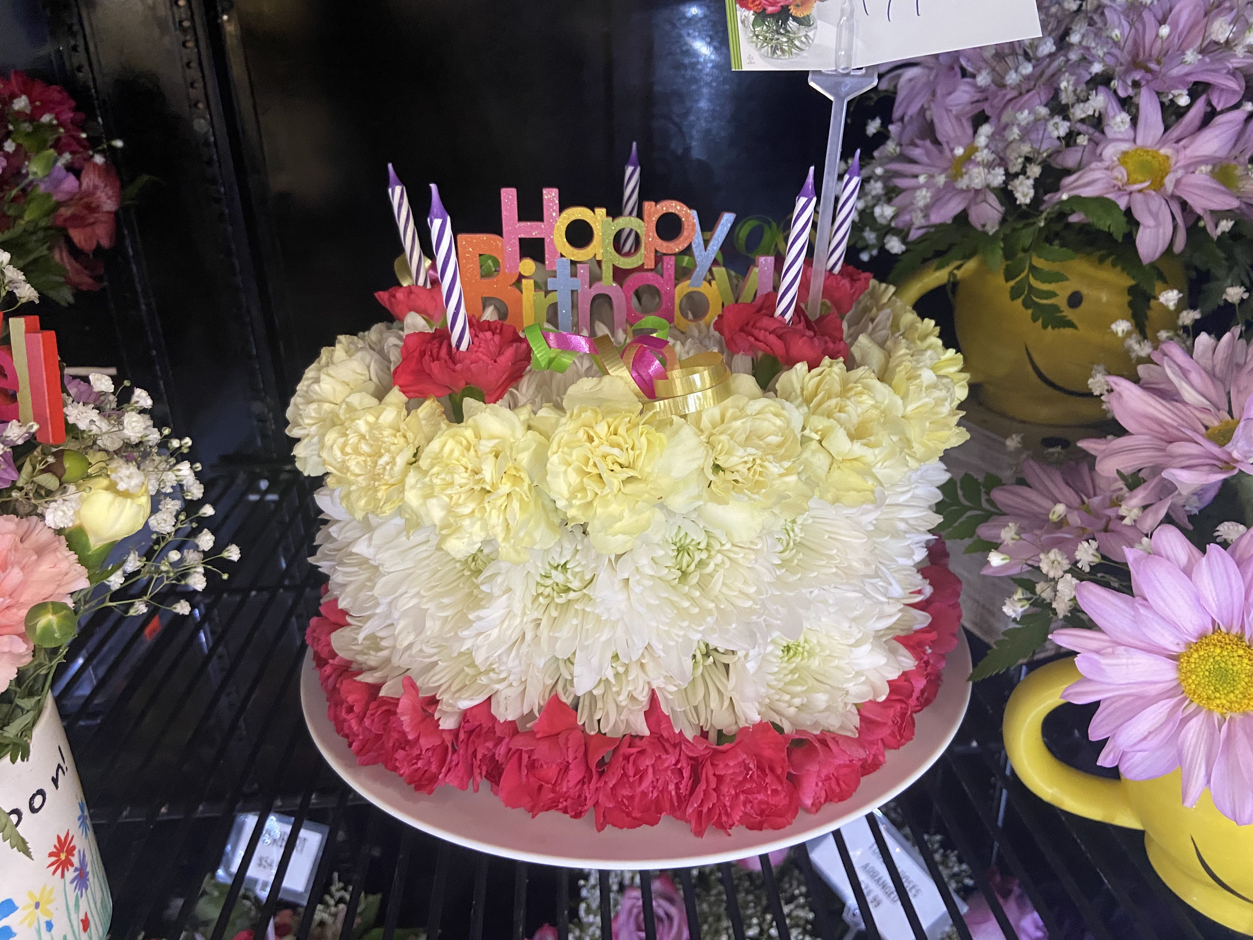 Flower Birthday Cake Flower Birthday Cake - All the joy, without the carbs! This arrangement uses fresh flowers to mimic the look of a birthday cake, candles and all.