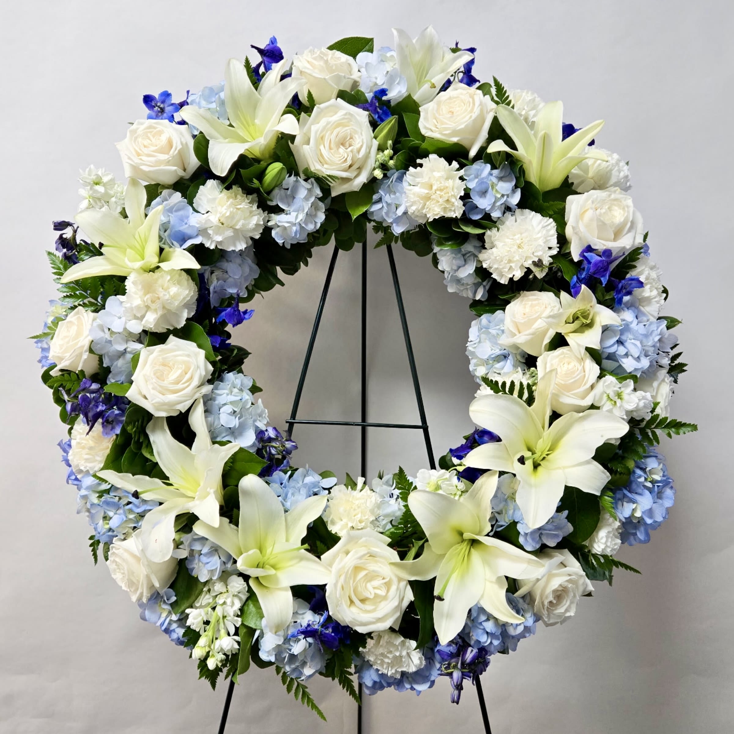 Blue Horizon Wreath - This 21&quot; Wreath Includes White Lily's, White Roses. White Stock, White Carnation, Blue Hydrangea and Blue Delphinium. Or as Similar as Possible. 