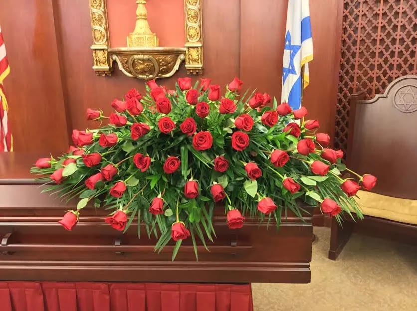 The Red Rose Casket Spray (6 dozen shown) The Red Rose Casket Spray (6 dozen shown) - Express love, devotion, and respect with the timeless beauty of this red rose casket spray, a stunning funeral flower arrangement designed for a full couch or closed casket service. Featuring six dozen premium red Freedom roses, this impressive display creates a bold and elegant tribute to honor a life well lived. Available in other rose colors upon request, please call us at (818) 763-6993 for details. This item is NOT available for same-day delivery.