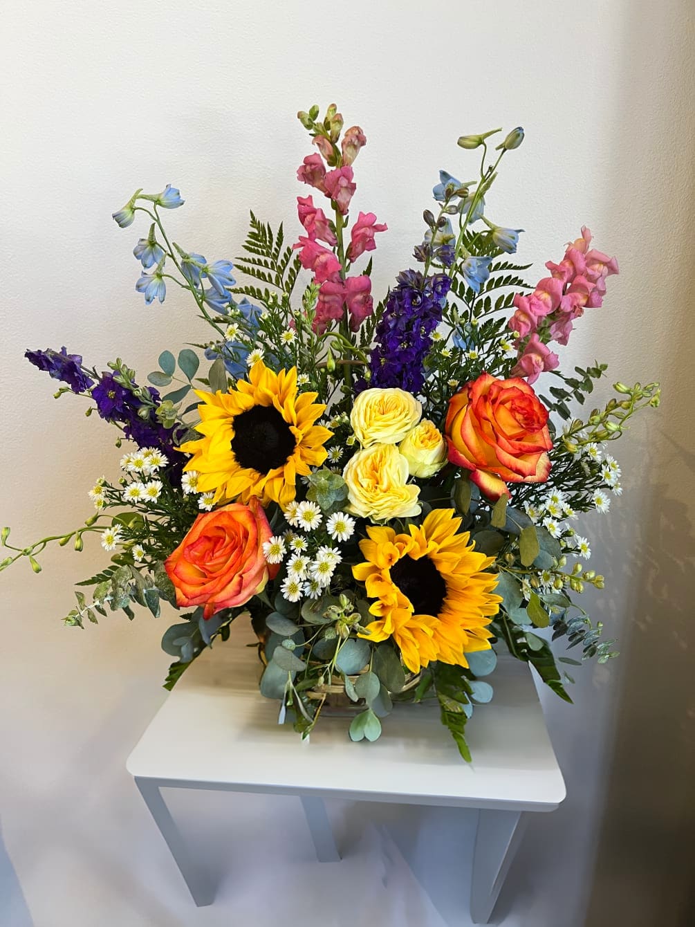 Summer Basket Summer Basket - A beautiful summer bouquet in a basket with sunflowers, snapdragons, delphinium, larkspur, roses and gunni eucalyptus.
